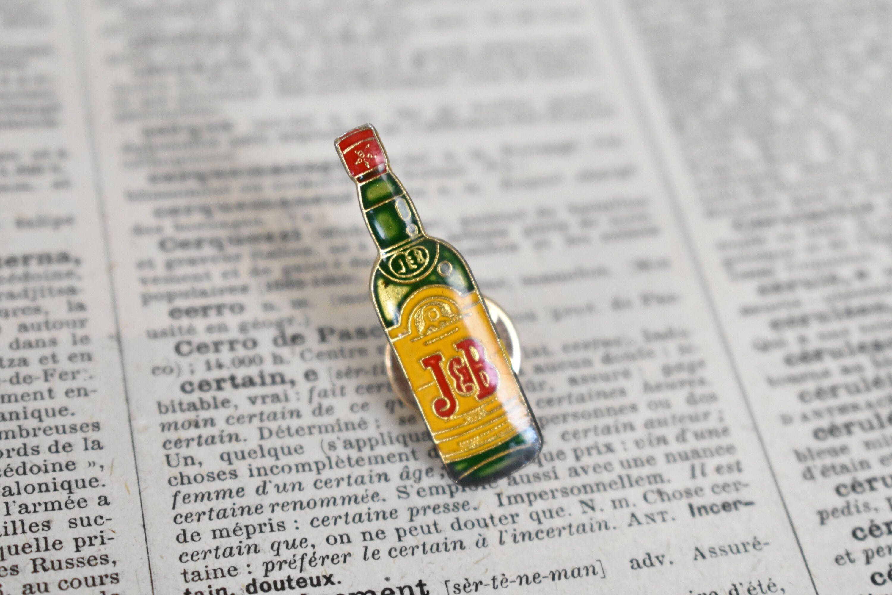 drinks 桌布 壁紙 — 一個微型J&B威士忌酒瓶別針放在打開的法文詞典頁上。
