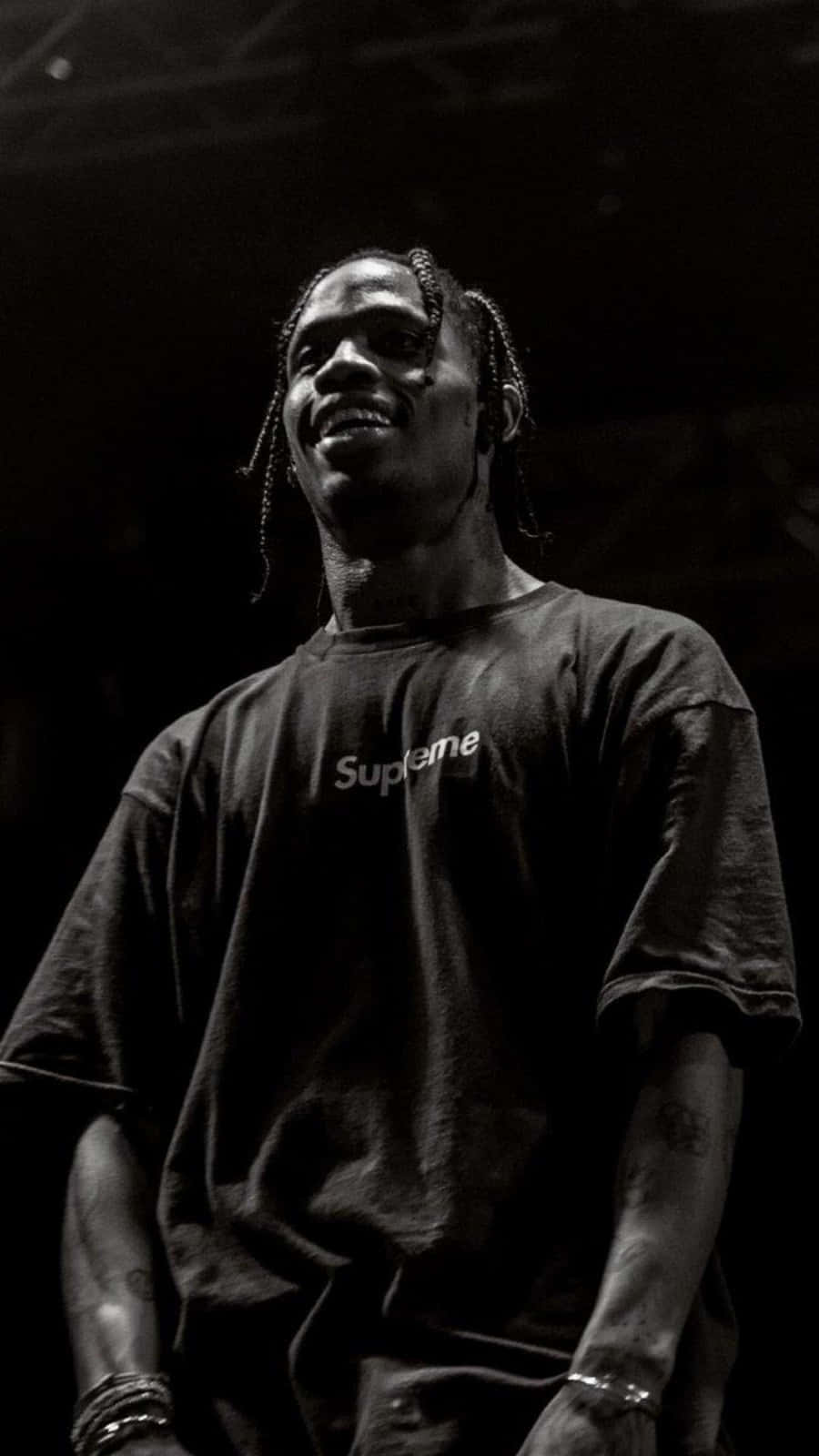 桌布 壁紙 — 一個微笑、編辮子的男人穿著Supreme T恤，在深色背景前的黑白肖像。