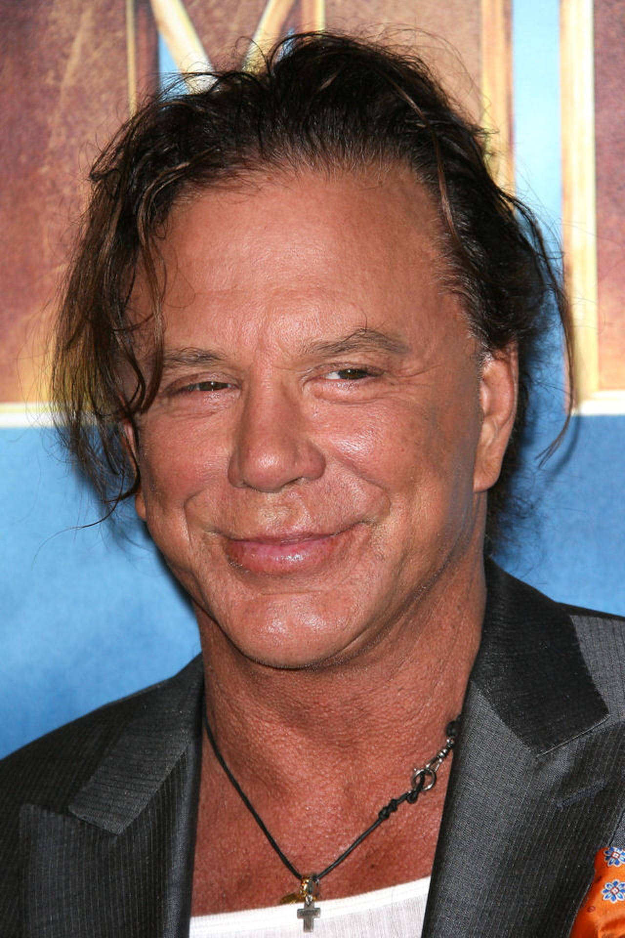 Celebrity 桌布 壁紙 — 一個微笑男人的特寫肖像，頭髮凌亂深色，身穿黑色西裝外套和十字架項鍊，背景為藍色和金色。