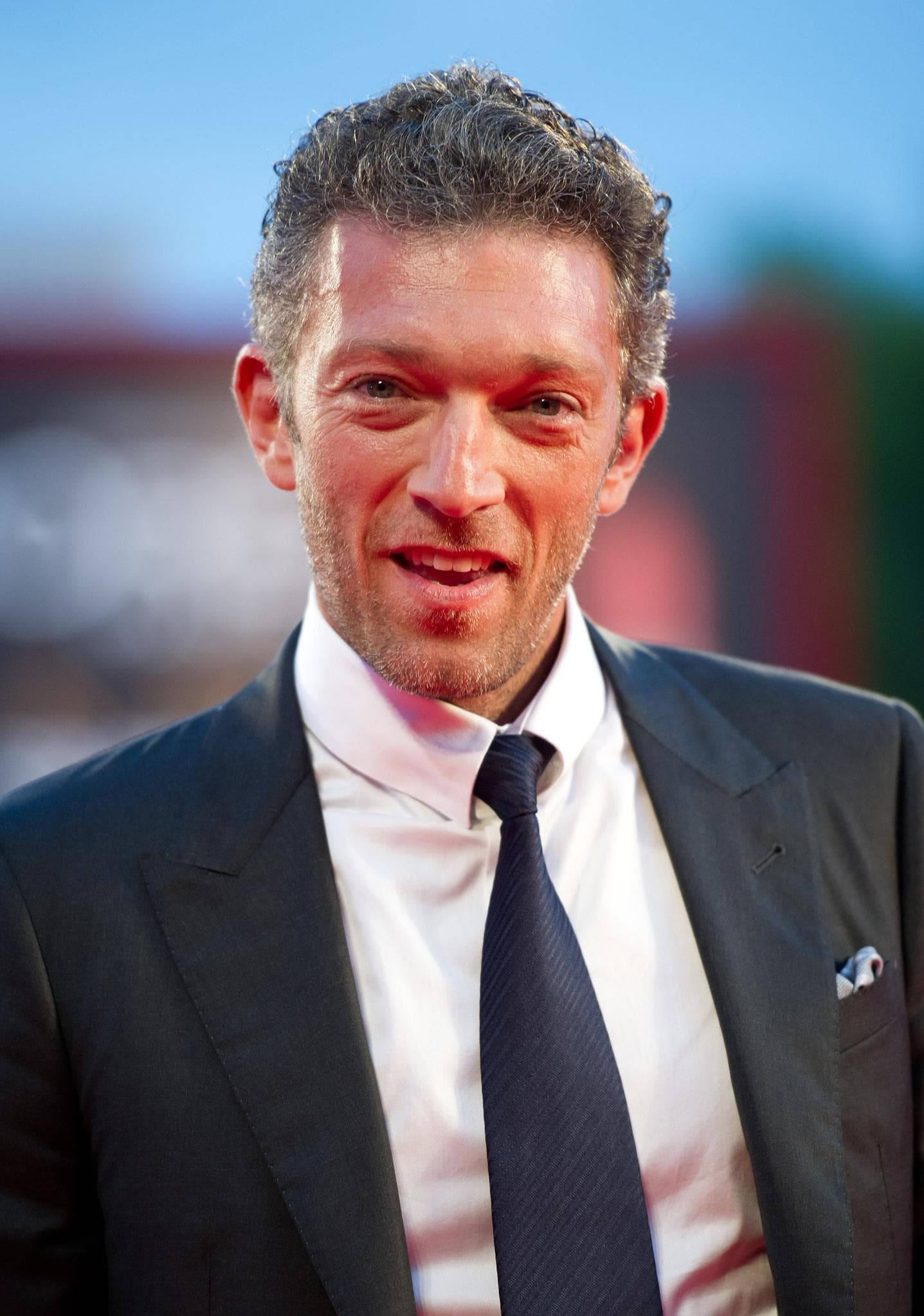 actor 桌布 壁紙 — 一個微笑男士的近距離肖像，身穿深色西裝和領帶，背景是模糊多彩的。