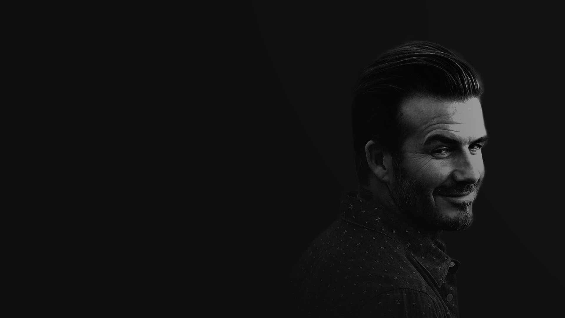 David Beckham 桌布 壁紙 — 一個微笑男子的單色肖像，他有造型頭髮和鬍鬚，背景是深色。