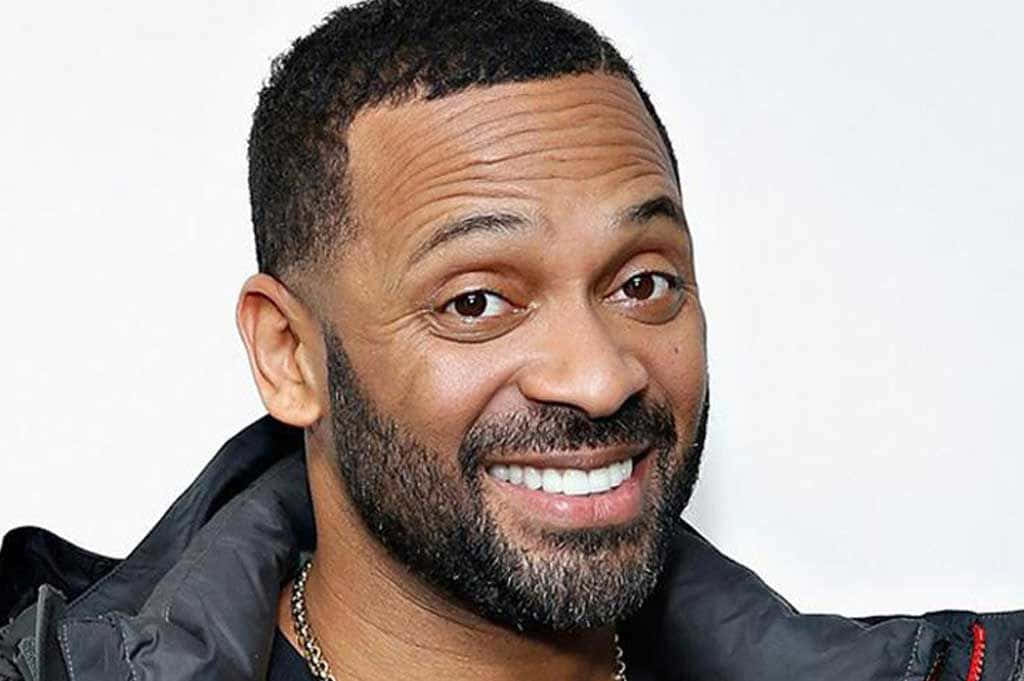 Mike Epps 桌布 壁紙 — 一個微笑留鬍鬚的男人穿著深色外套，在純白色背景前的特寫肖像。