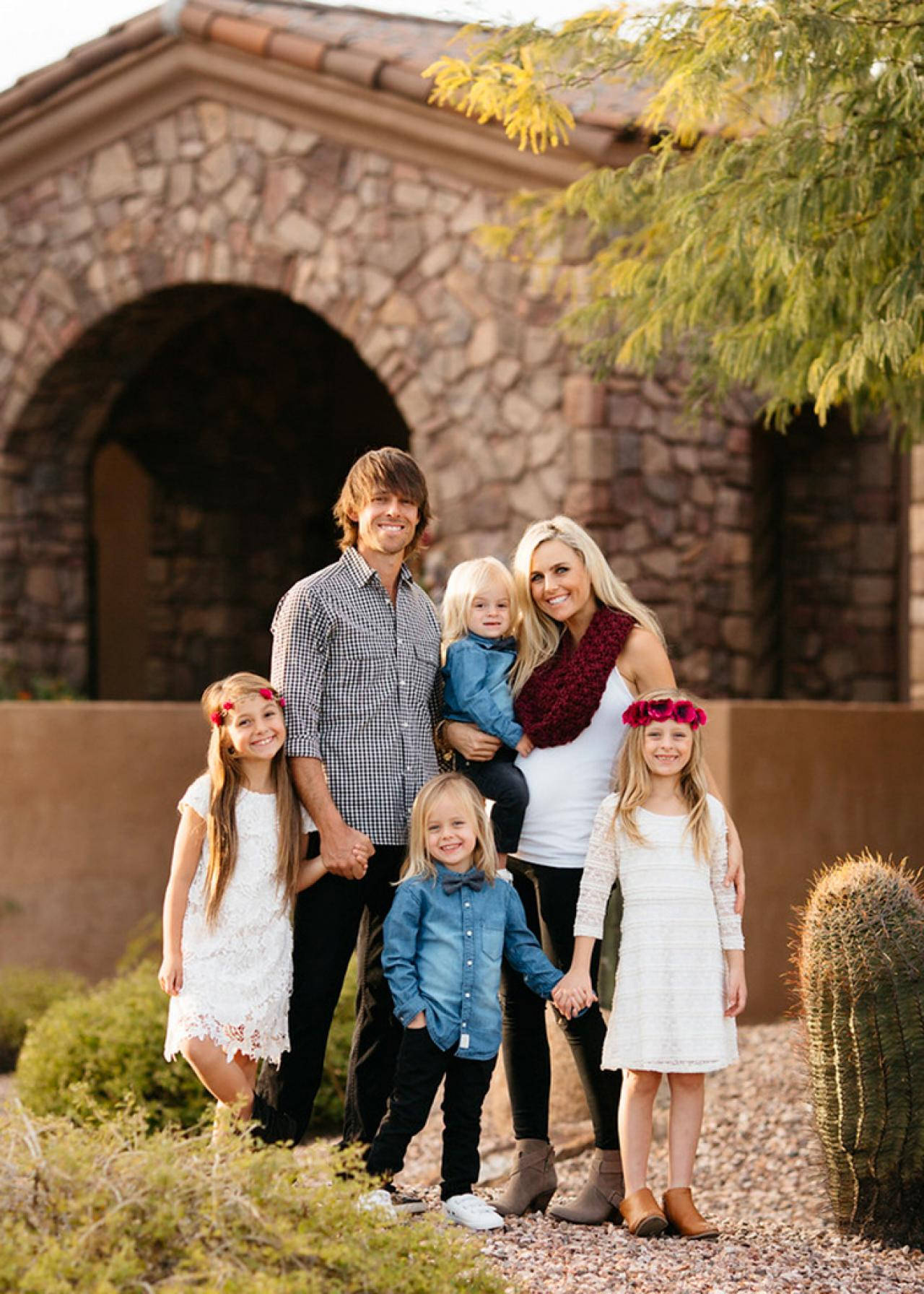 Family 桌布 壁紙 — 一個微笑的六人家庭在溫暖的金色光線下，在一個有沙漠植物和仙人掌的石拱門前一起戶外擺姿勢。