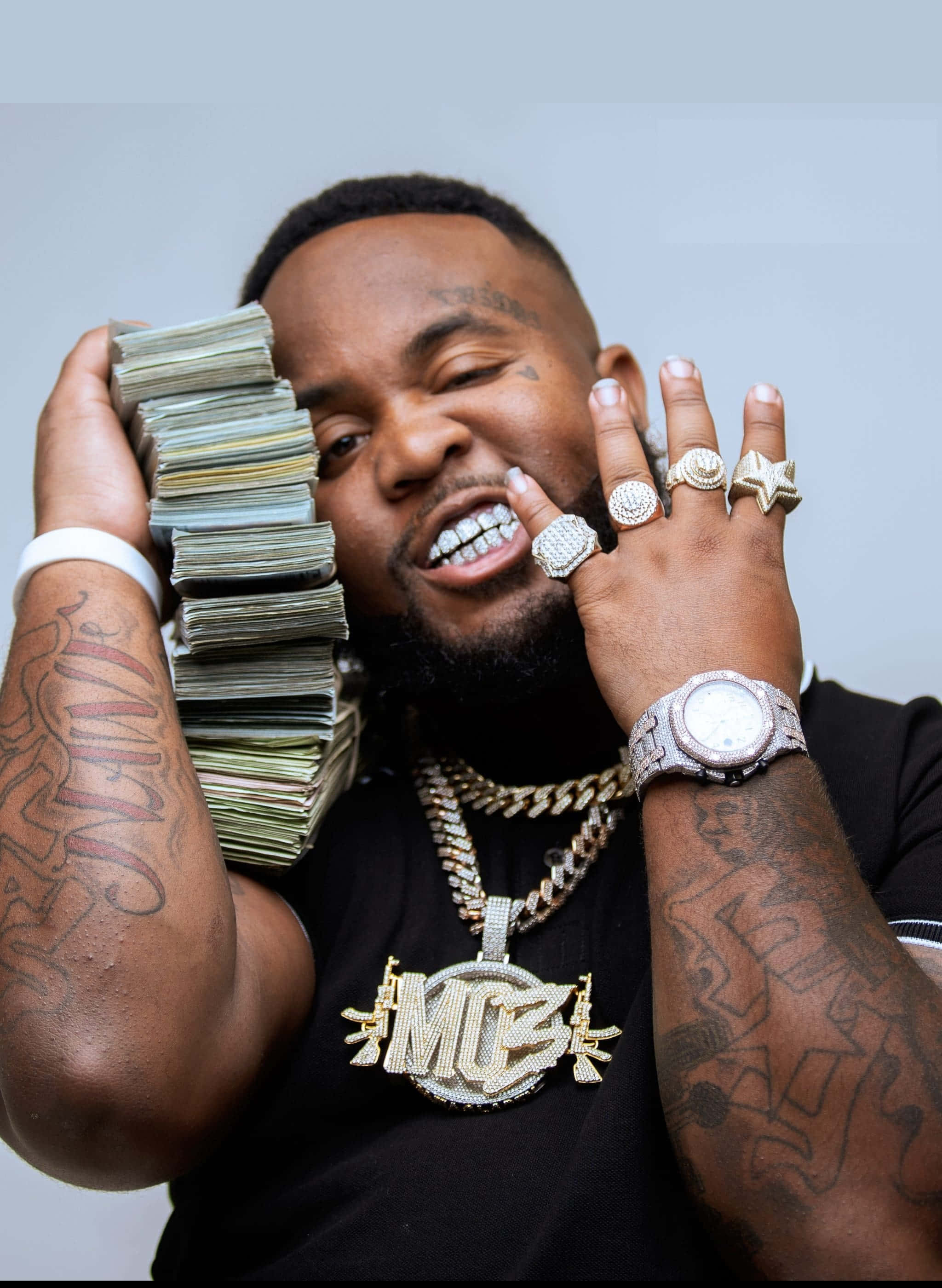 Rappers 桌布 壁紙 — 一個微笑的刺青男子拿著一大疊現金，同時閃耀著鑽石戒指和一條大金鍊。