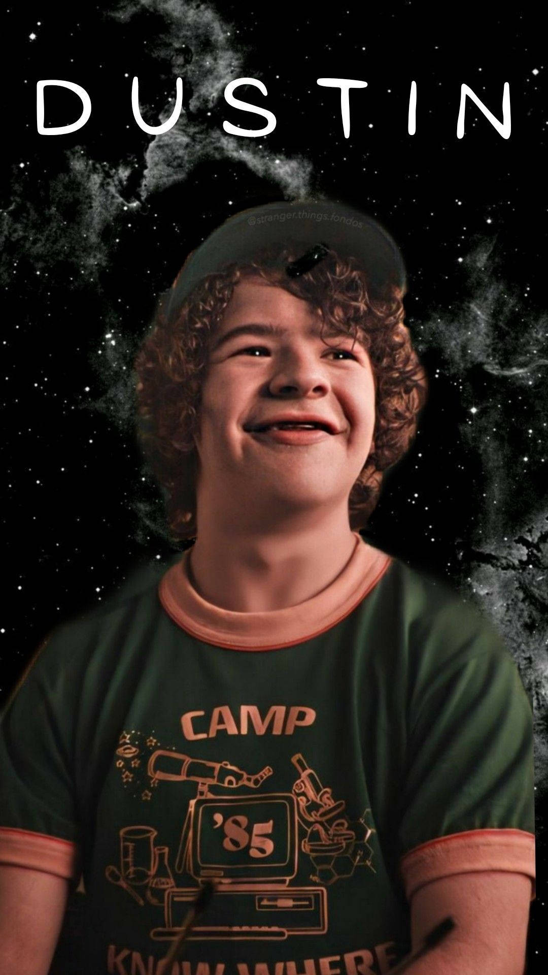 Dustin Stranger Things 桌布 壁紙 — 一個微笑的年輕男孩，捲髮，穿著綠色營地T恤，背景是星空宇宙，白色文字寫著名字Dustin。