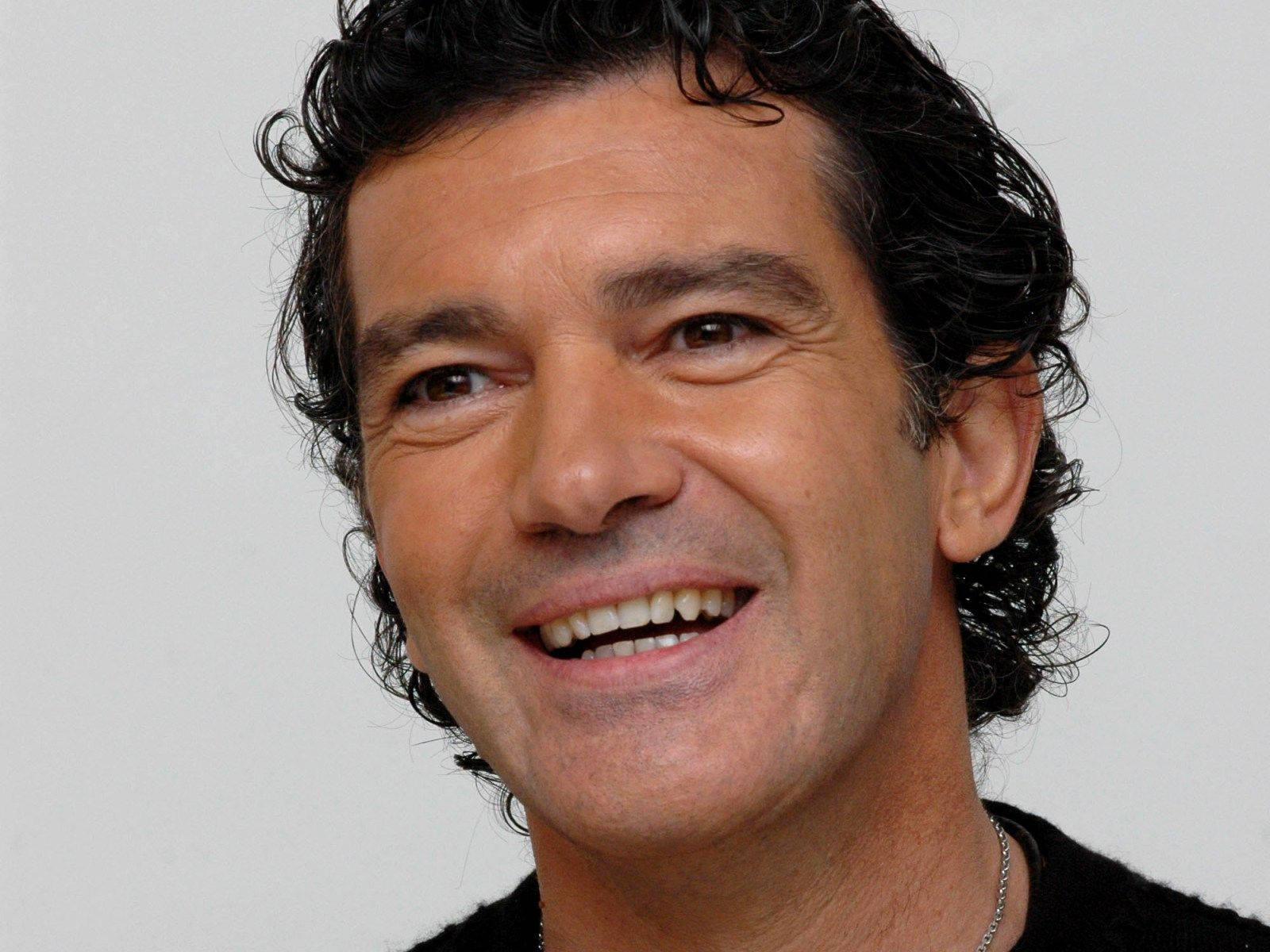 antonio banderas 桌布 壁紙 — 一個微笑的男人，有深色捲髮，在純白色背景前的特寫肖像。