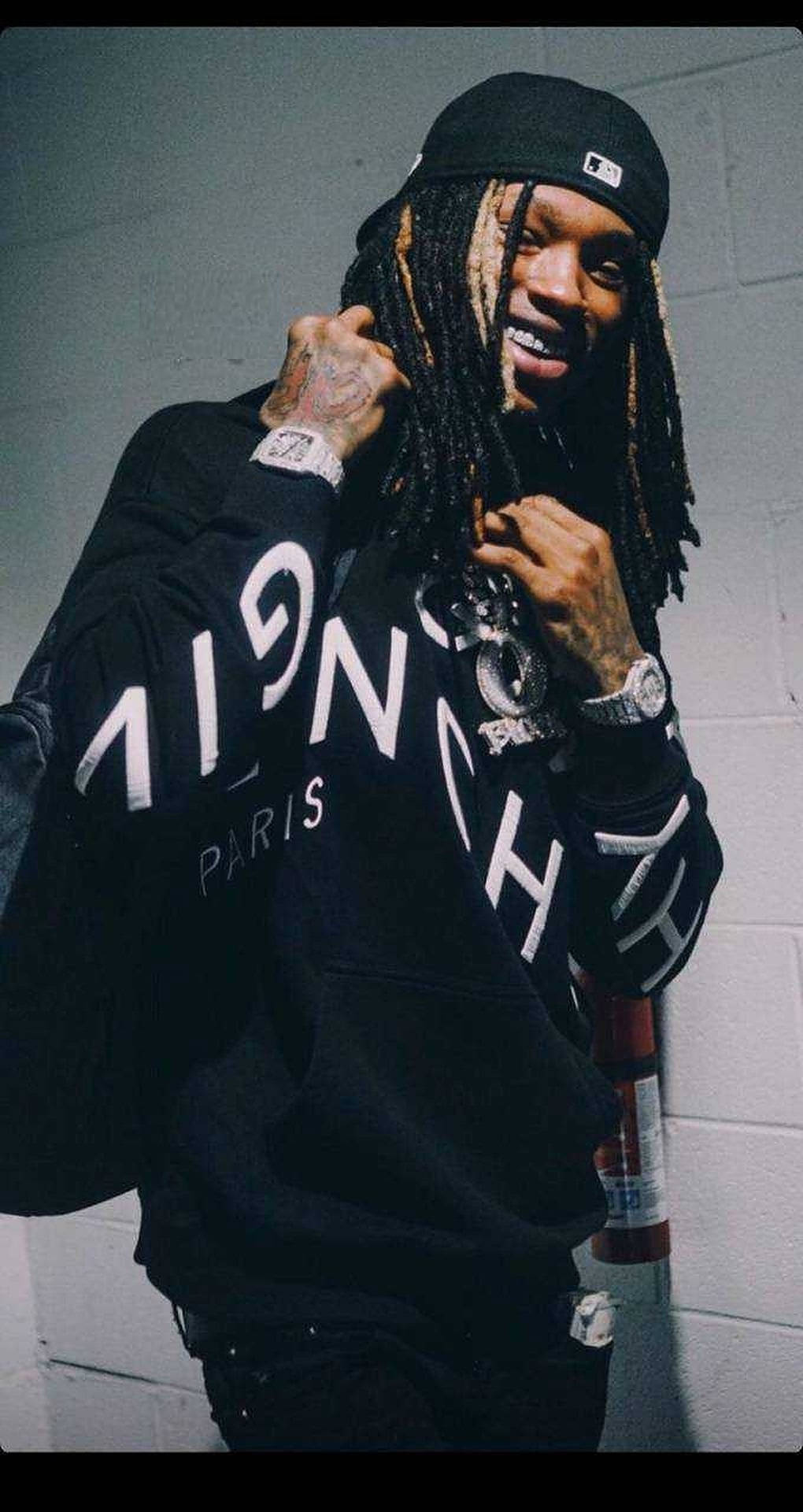 留著辮子頭和刺青的男人，穿著黑色連帽衫，以磚牆為背景。 — King Von 壁紙