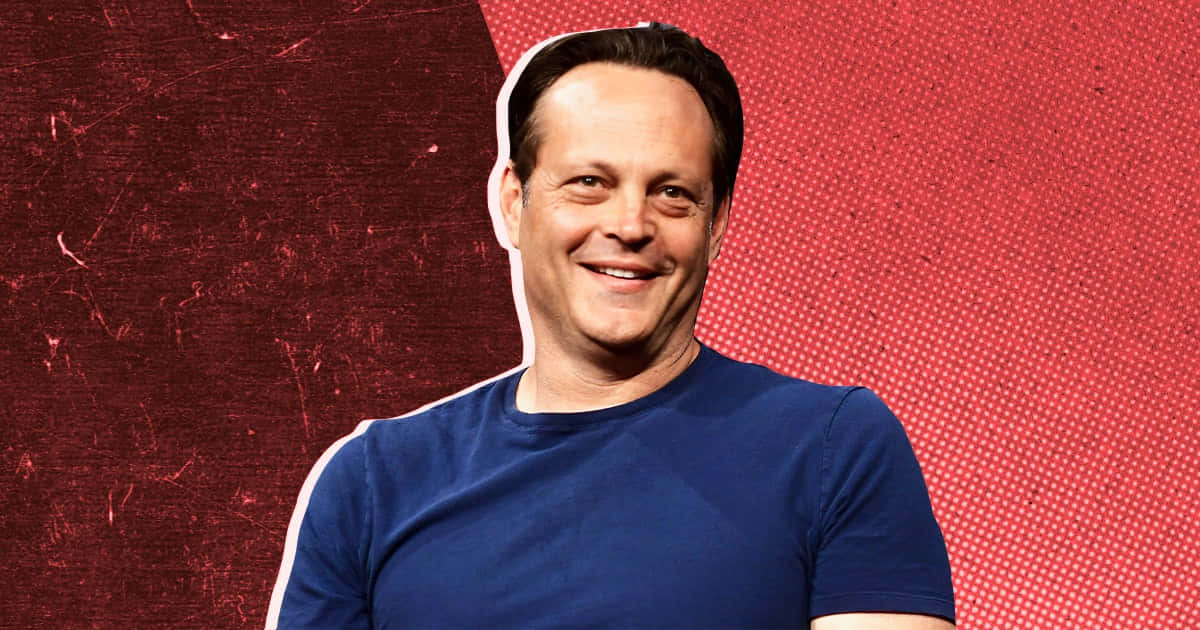 Vince Vaughn 桌布 壁紙 — 一個微笑的男人，身穿藍色T恤，站在有圓點圖案的紋理紅色背景前面。
