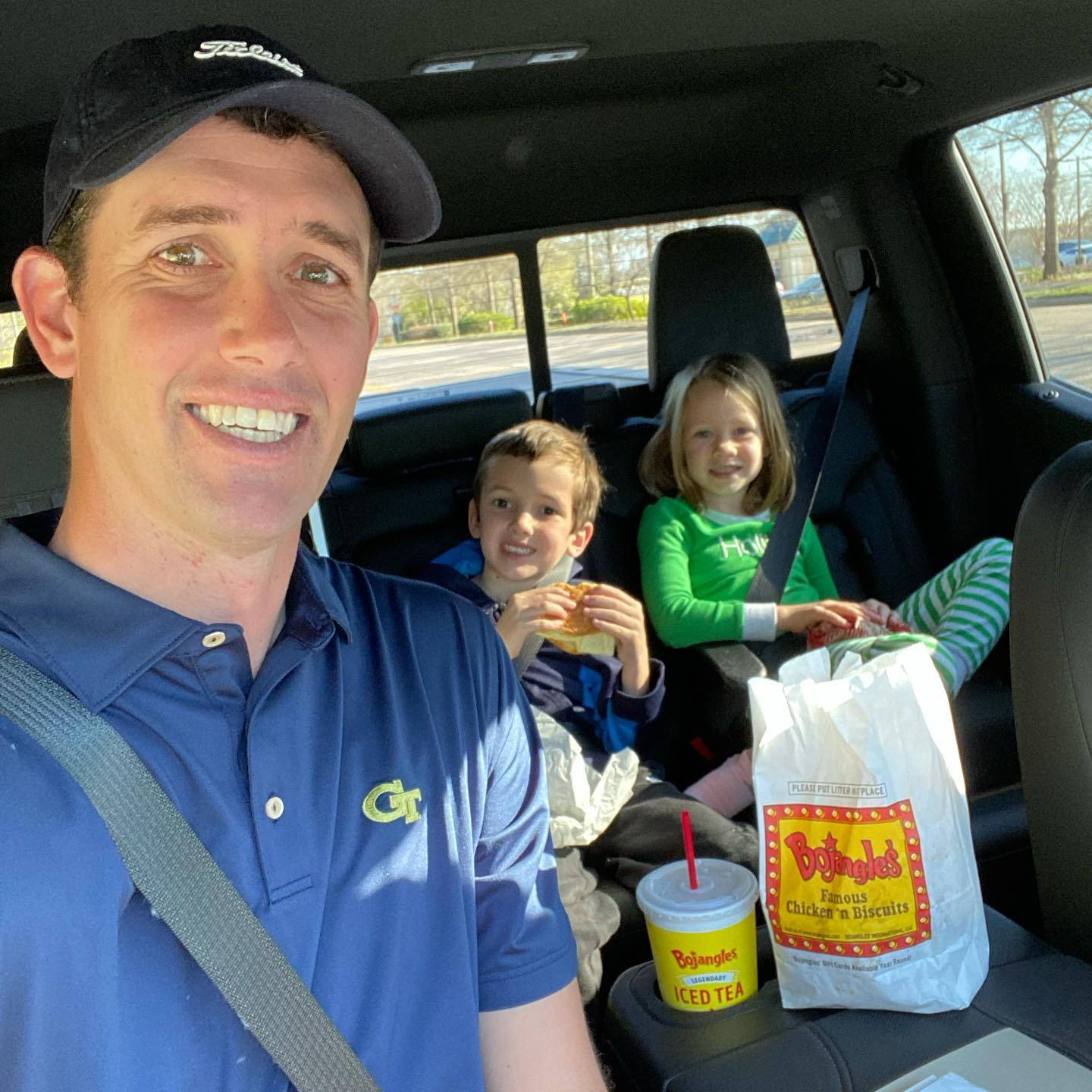 Family 桌布 壁紙 — 一個微笑的男人和兩個孩子在車內享受速食，陽光透過車窗灑進來。