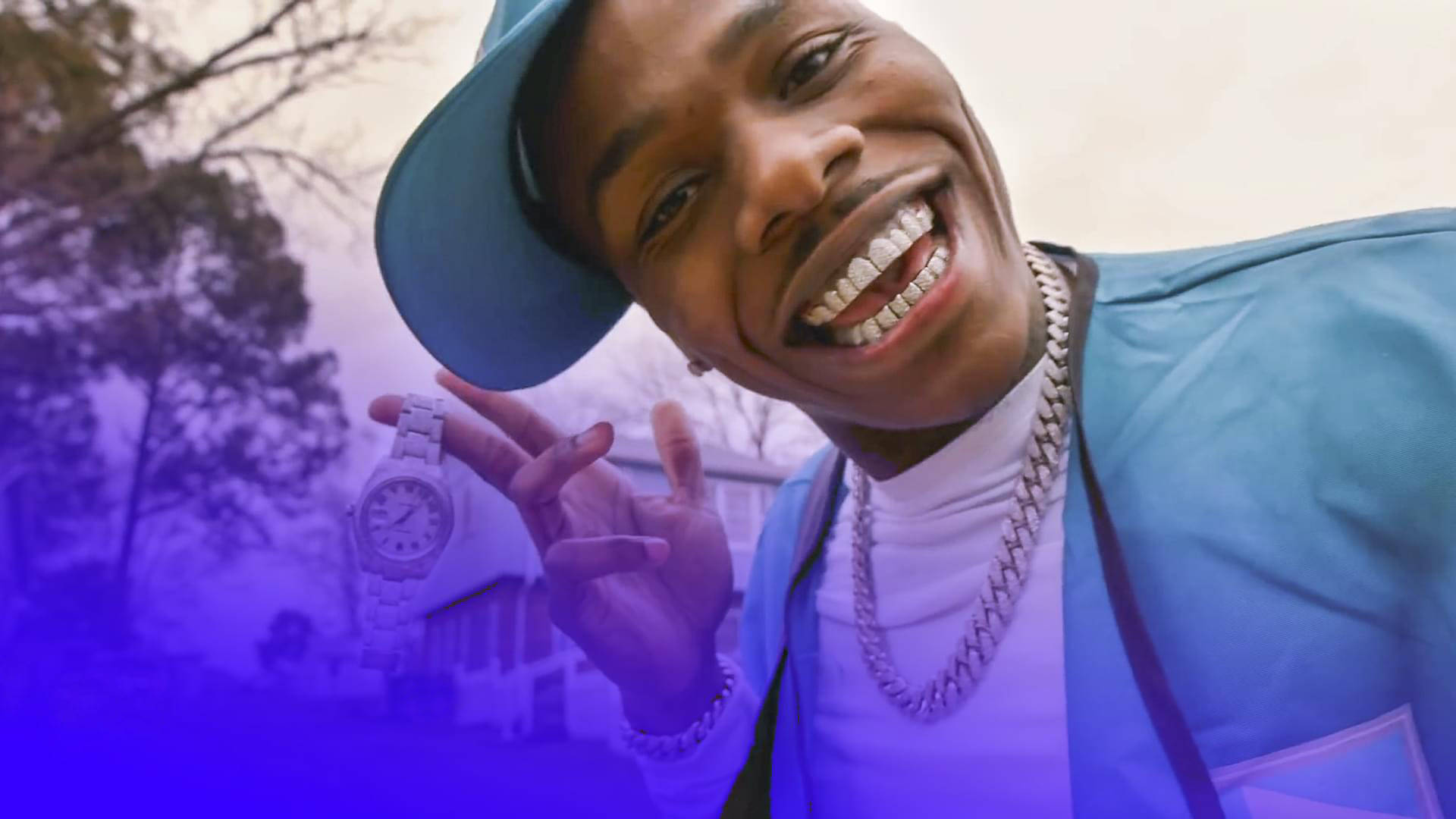 Dababy 桌布 壁紙 — 一個微笑的男人戴著藍色帽子和夾克，在紫色郊區背景下炫耀鑲鑽手錶。