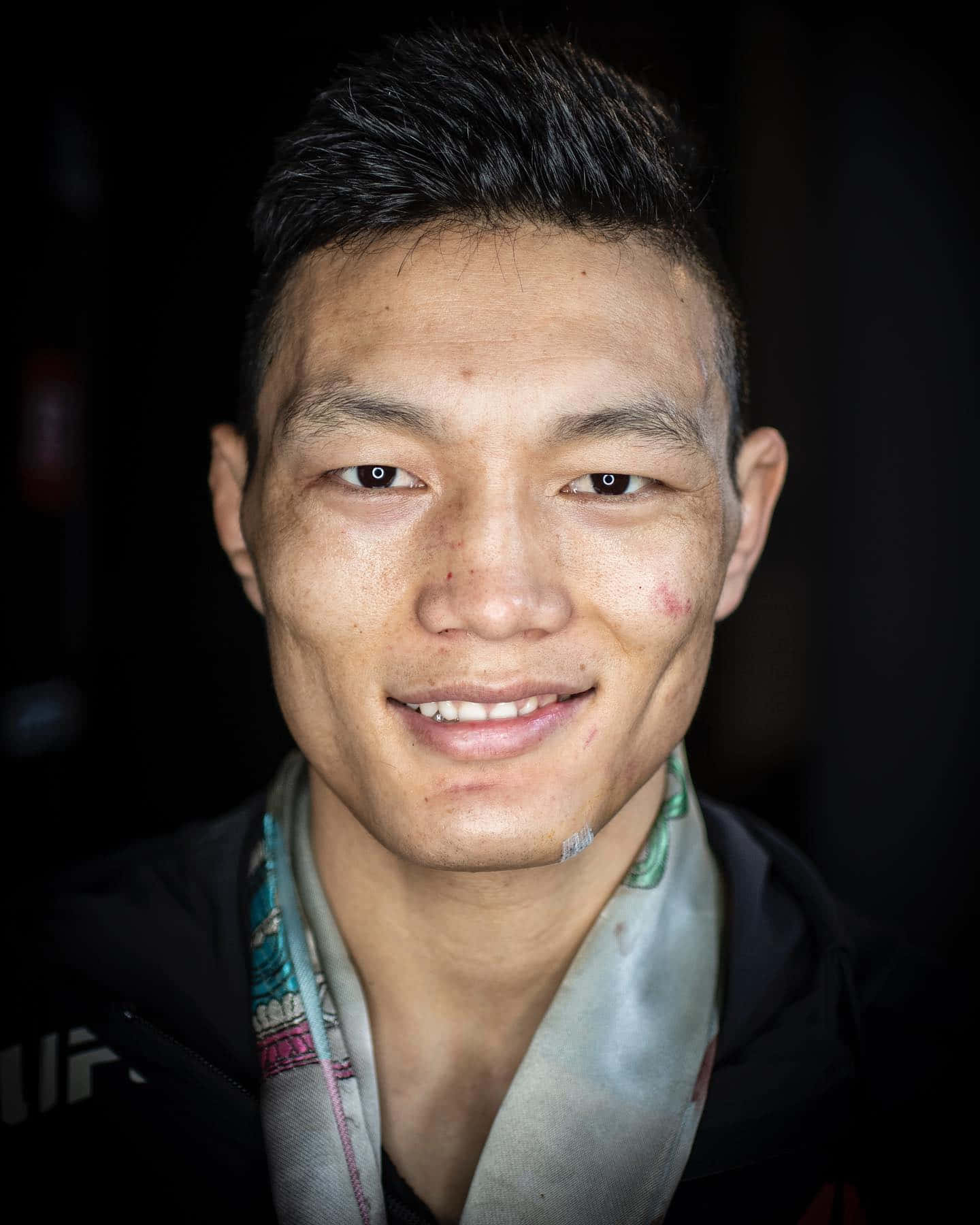 Smile 桌布 壁紙 — 一個微笑的男人特寫肖像，短黑髮，戴著彩色圍巾，背景為深色。