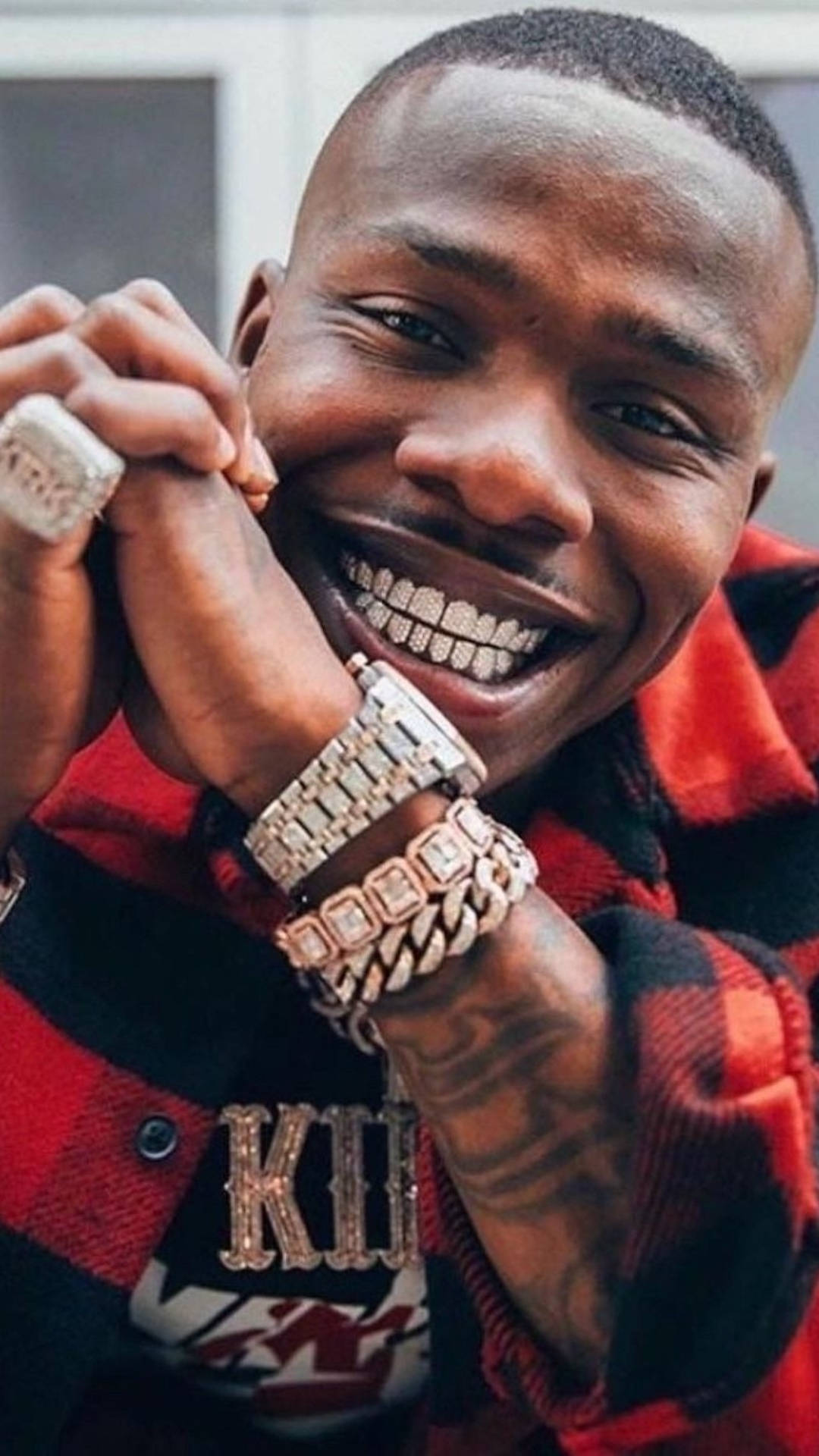 Hip Hop 桌布 壁紙 — 一個微笑的男人穿著紅色格紋襯衫，展示他鑲滿鑽石的牙套和奢華珠寶。