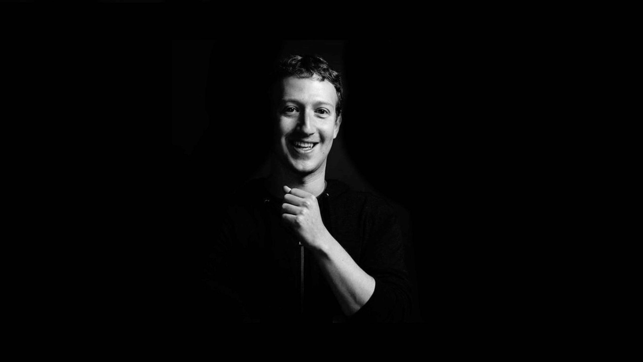 Zuckerberg 桌布 壁紙 — 一個微笑的男人黑白肖像，一隻手靠近下巴，背景黑暗。