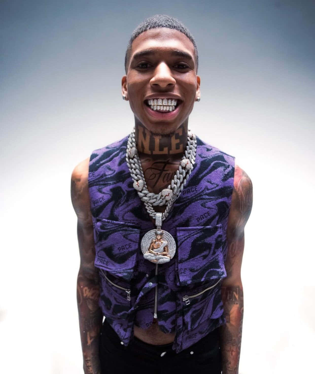 有刺青和鑽石牙套的男子，穿著紫色背心和粗鏈條。 — NLE Choppa GIF 壁紙