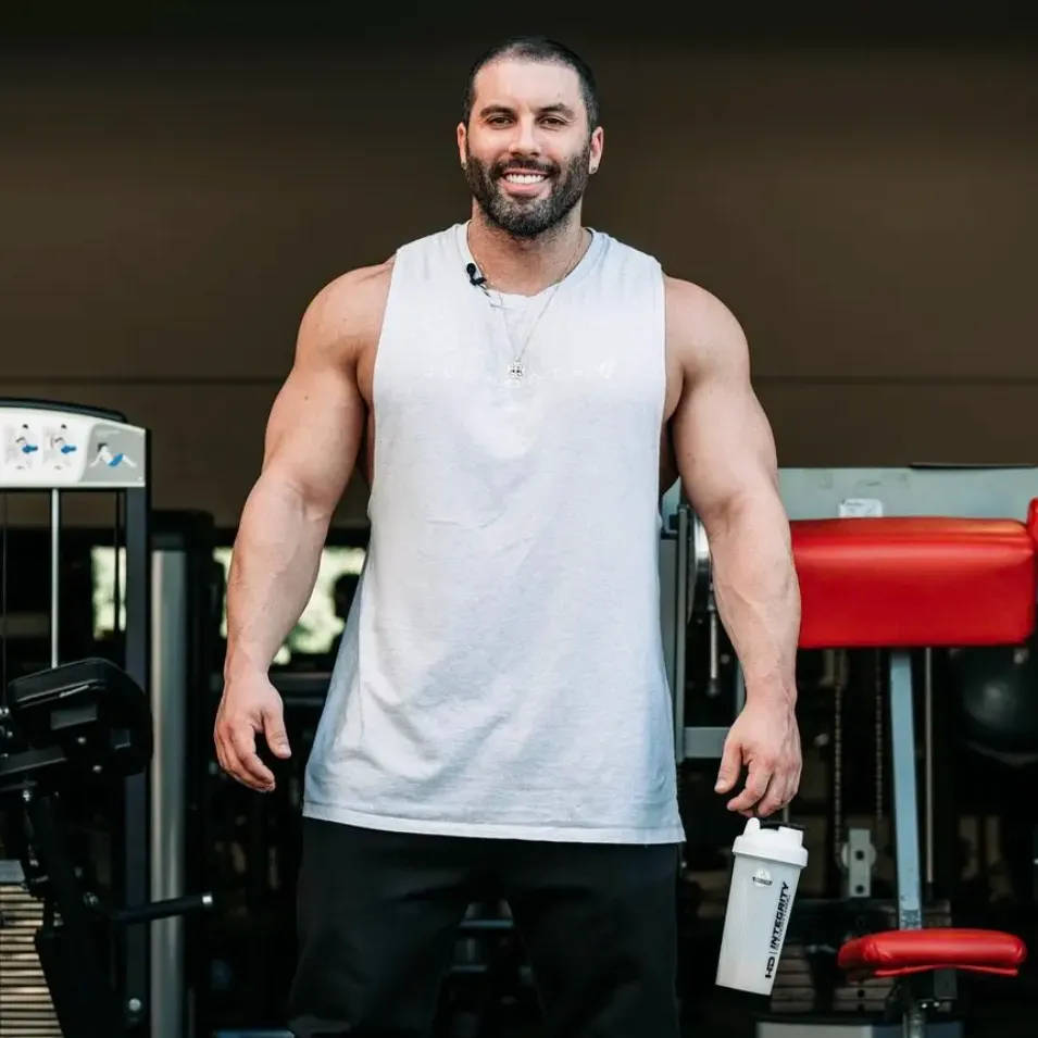 Exercise 桌布 壁紙 — 一個微笑的肌肉男在健身房裡，站在健身器材前，手持一個白色搖搖杯。