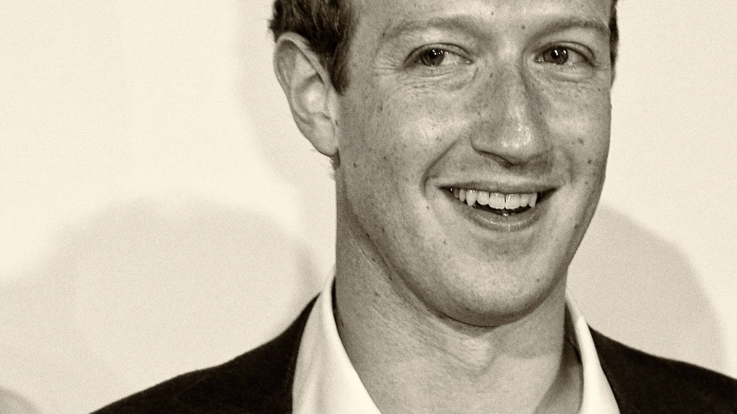 Zuckerberg 桌布 壁紙 — 一個微笑西裝男士的黑白特寫肖像，背景簡潔。