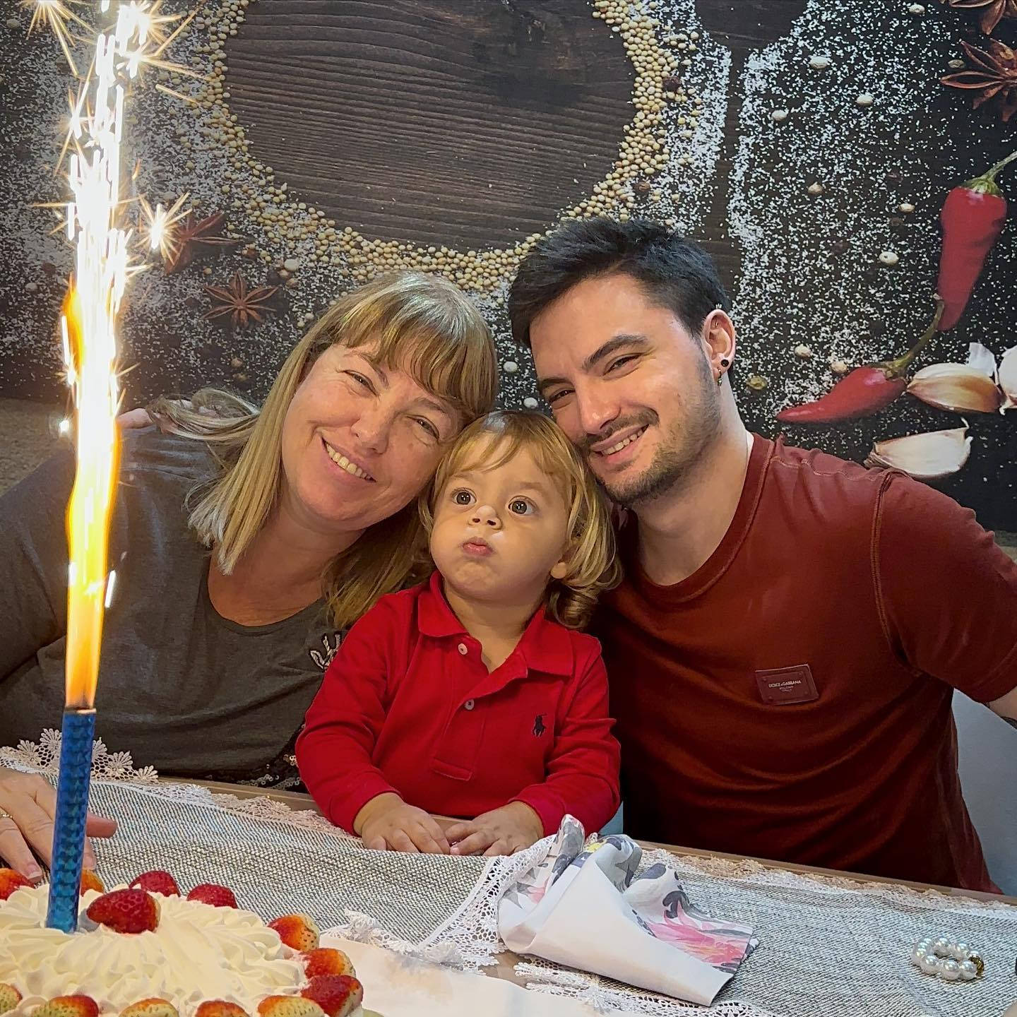 Birthday 桌布 壁紙 — 一個快樂的三口之家圍著一個帶有閃爍蠟燭的生日蛋糕微笑。