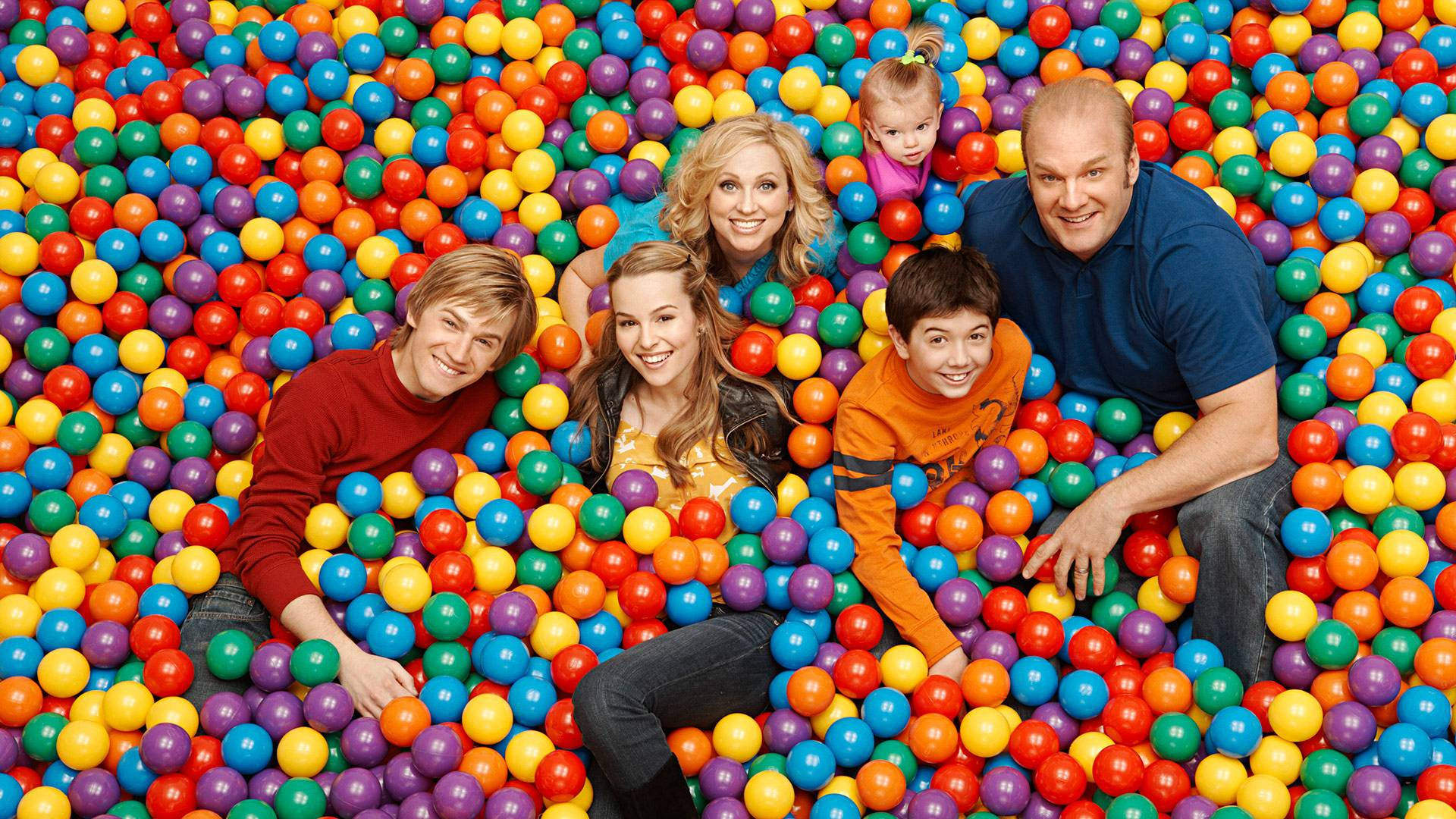 Good Luck Charlie 桌布 壁紙 — 一個快樂的六口之家在充滿活力的彩色塑膠球海中微笑。