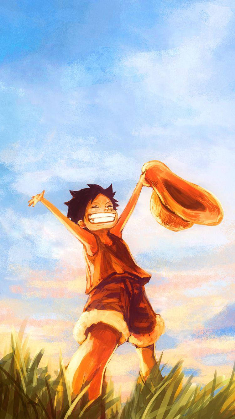 One Piece Phone 桌布 壁紙 — 一個快樂的動漫男孩，頭髮尖尖，在明亮的藍天下跳躍在草地上，雙臂高舉，帽子高高拋起。
