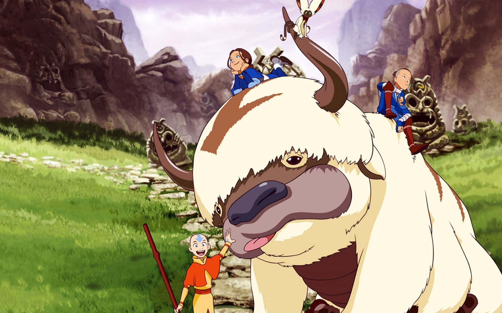 Appa Avatar 桌布 壁紙 — 一個快樂的動畫場景，有一隻大型白色牛科生物和三個年輕角色在一個多山的草地山谷中。