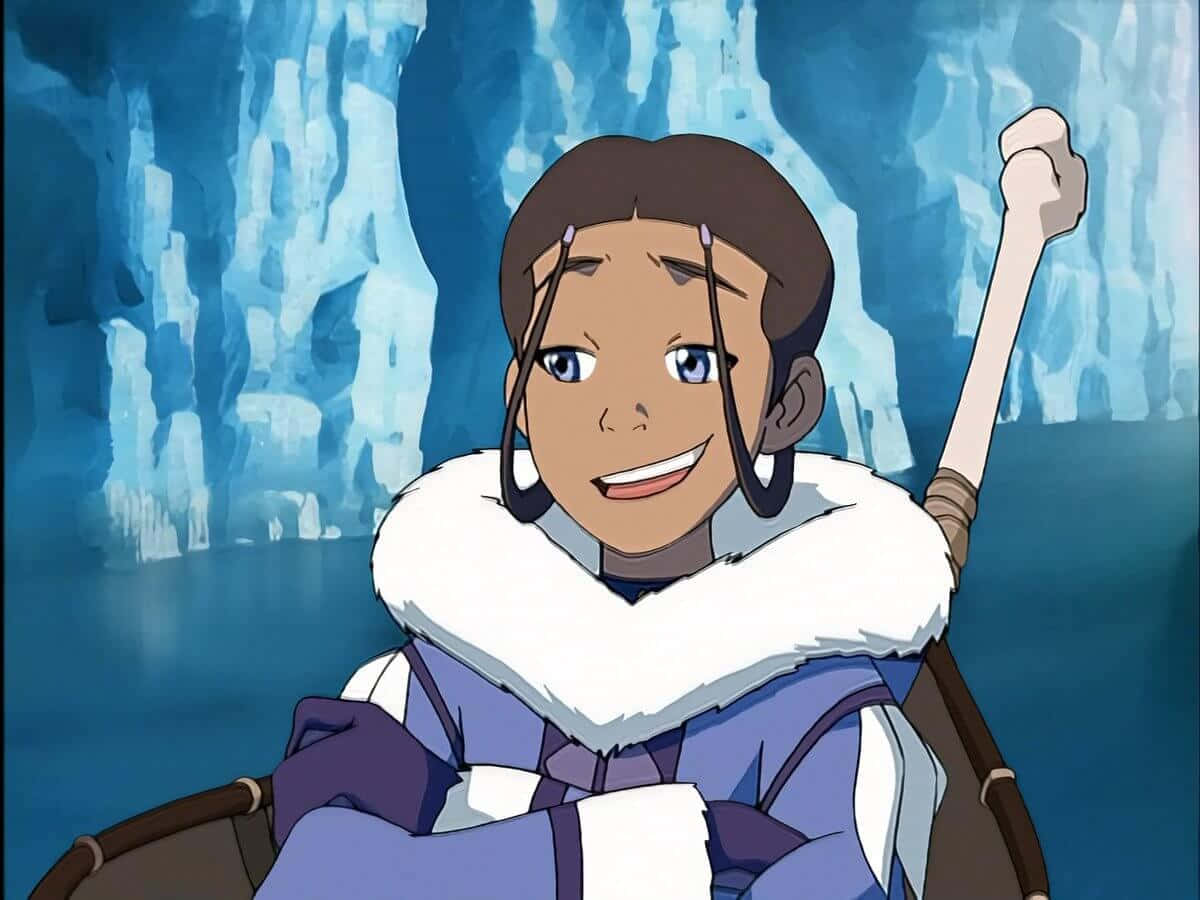 降世神通 最後的氣宗 桌布 壁紙 — 一個快樂的動畫女孩穿著毛皮襯裡的藍色外套，在冰冷的洞穴中微笑著拿著骨杖。