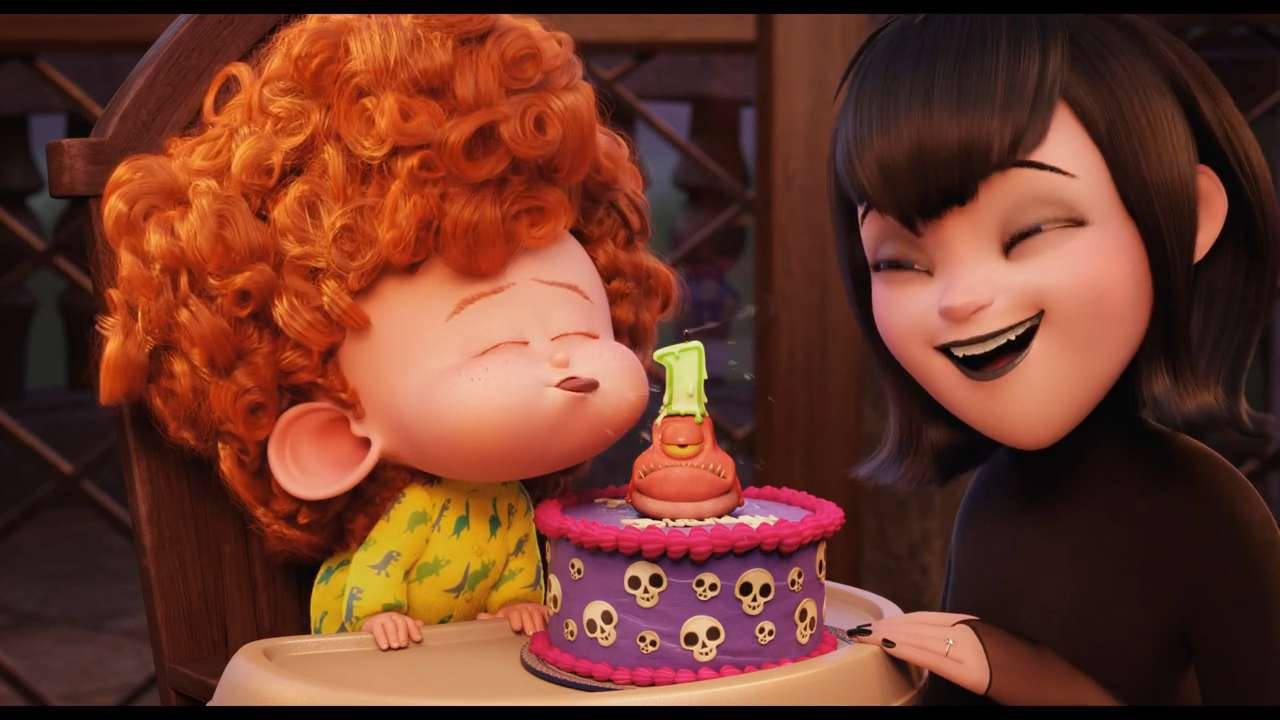 Animated 桌布 壁紙 — 一個快樂的動畫幼兒，有著捲曲的紅髮，親吻一個骷髏主題的生日蛋糕，而一個微笑的女人在看著。