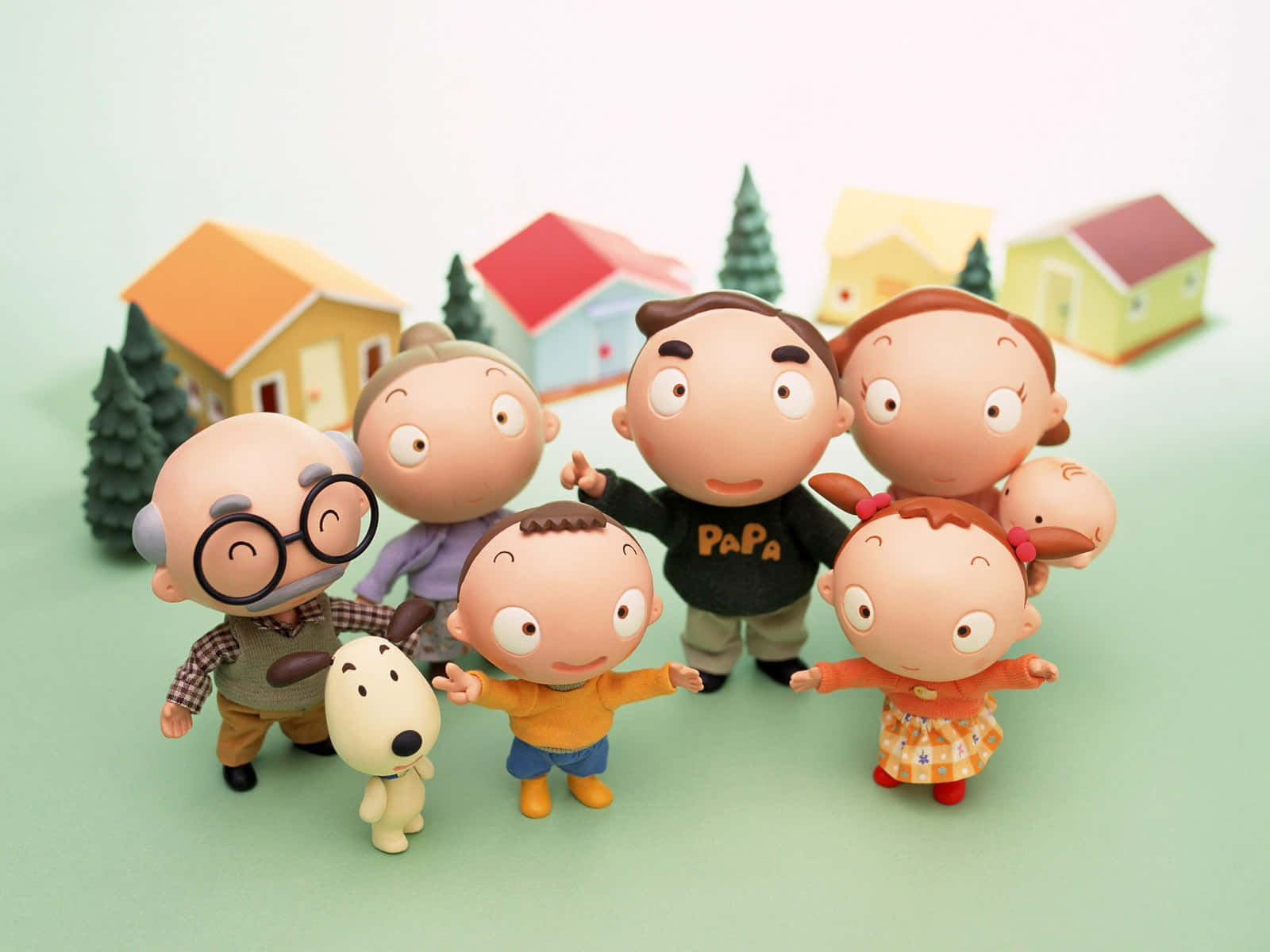 Family 桌布 壁紙 — 一個快樂的卡通人物家庭與一隻狗在微型房屋和樹木前合影。