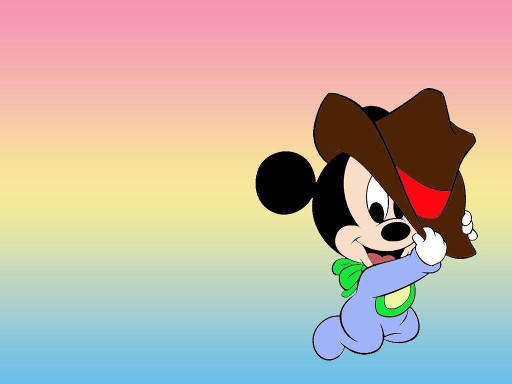 Mickey 桌布 壁紙 — 一個快樂的卡通嬰兒米奇老鼠，戴著棕色牛仔帽，穿著藍色衣服，在柔和的彩虹漸變背景上微笑。