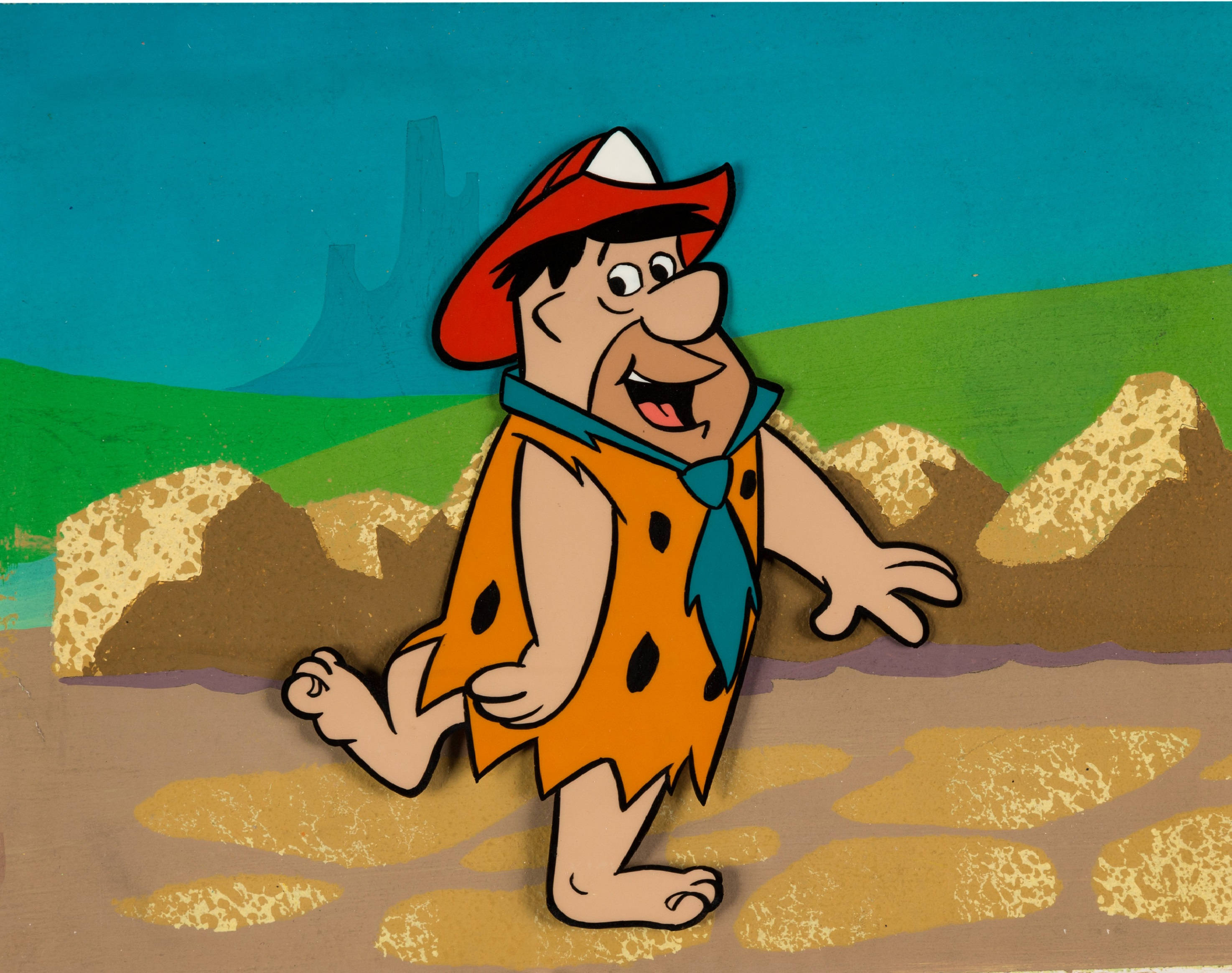 Flintstone 桌布 壁紙 — 一個快樂的卡通穴居人，穿著橙色斑點腰布和紅色帽子，赤腳走過岩石地形，身後有綠色山丘和藍天。
