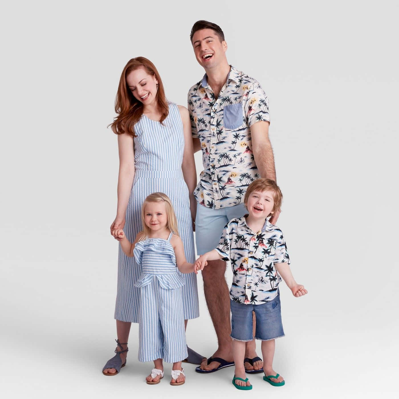 Family 桌布 壁紙 — 一個快樂的四口之家穿著相配的熱帶和條紋服裝在純白色背景前一起大笑。