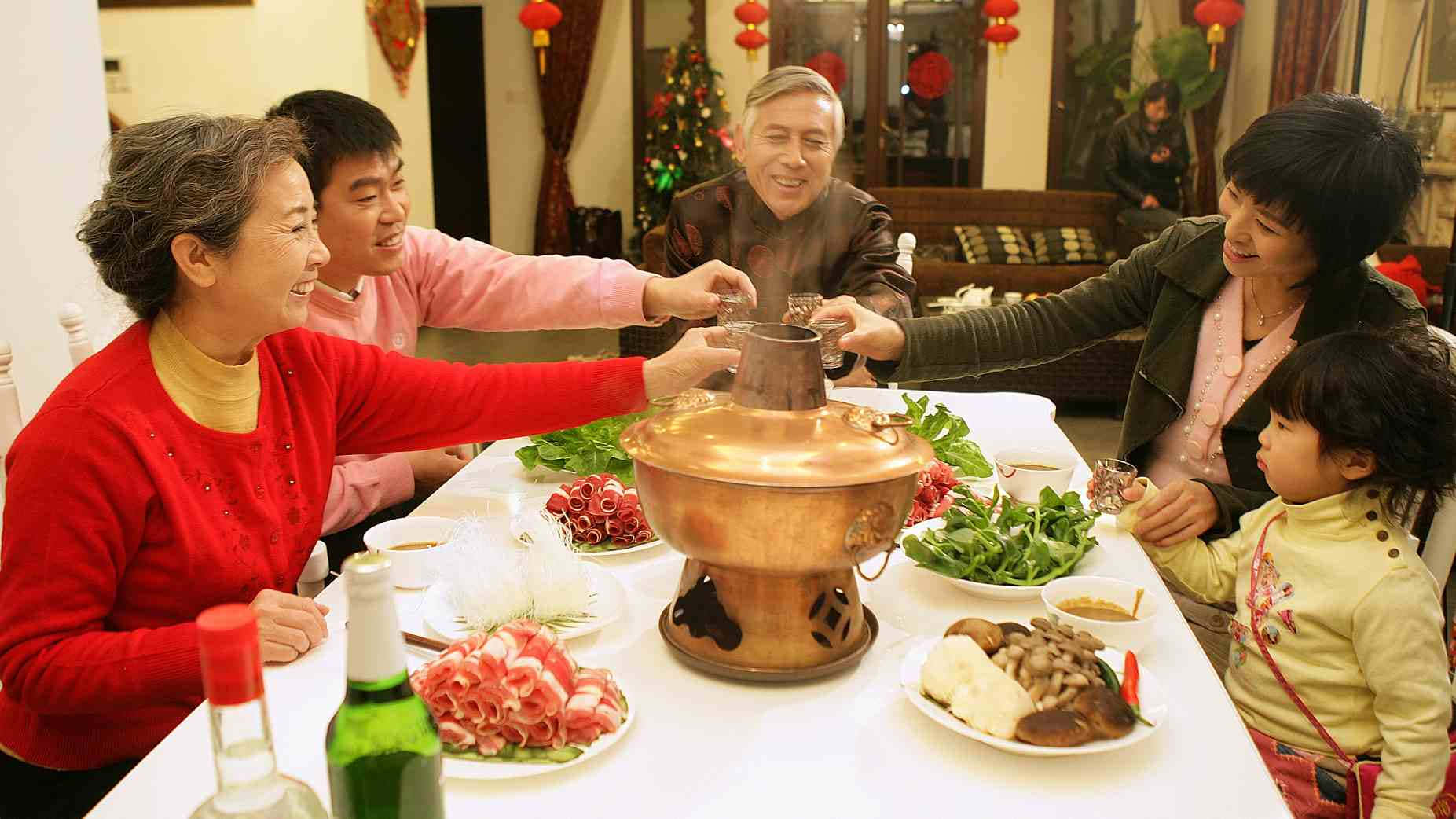Chinese Food 桌布 壁紙 — 一個快樂的多代家庭圍著一個冒煙的銅火鍋，在節日晚餐期間舉杯慶祝。