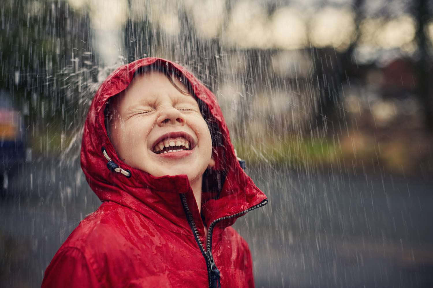 下雨 桌布 壁紙 — 一個快樂的孩子穿著紅色雨衣，在雨水灑落時閉著眼睛大笑。