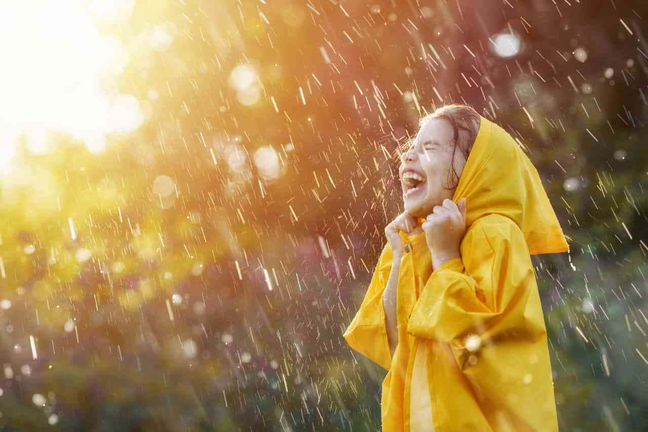 下雨 桌布 壁紙 — 一個快樂的孩子穿著鮮黃色雨衣，在金色陽光透過落下的雨滴時自由地大笑。