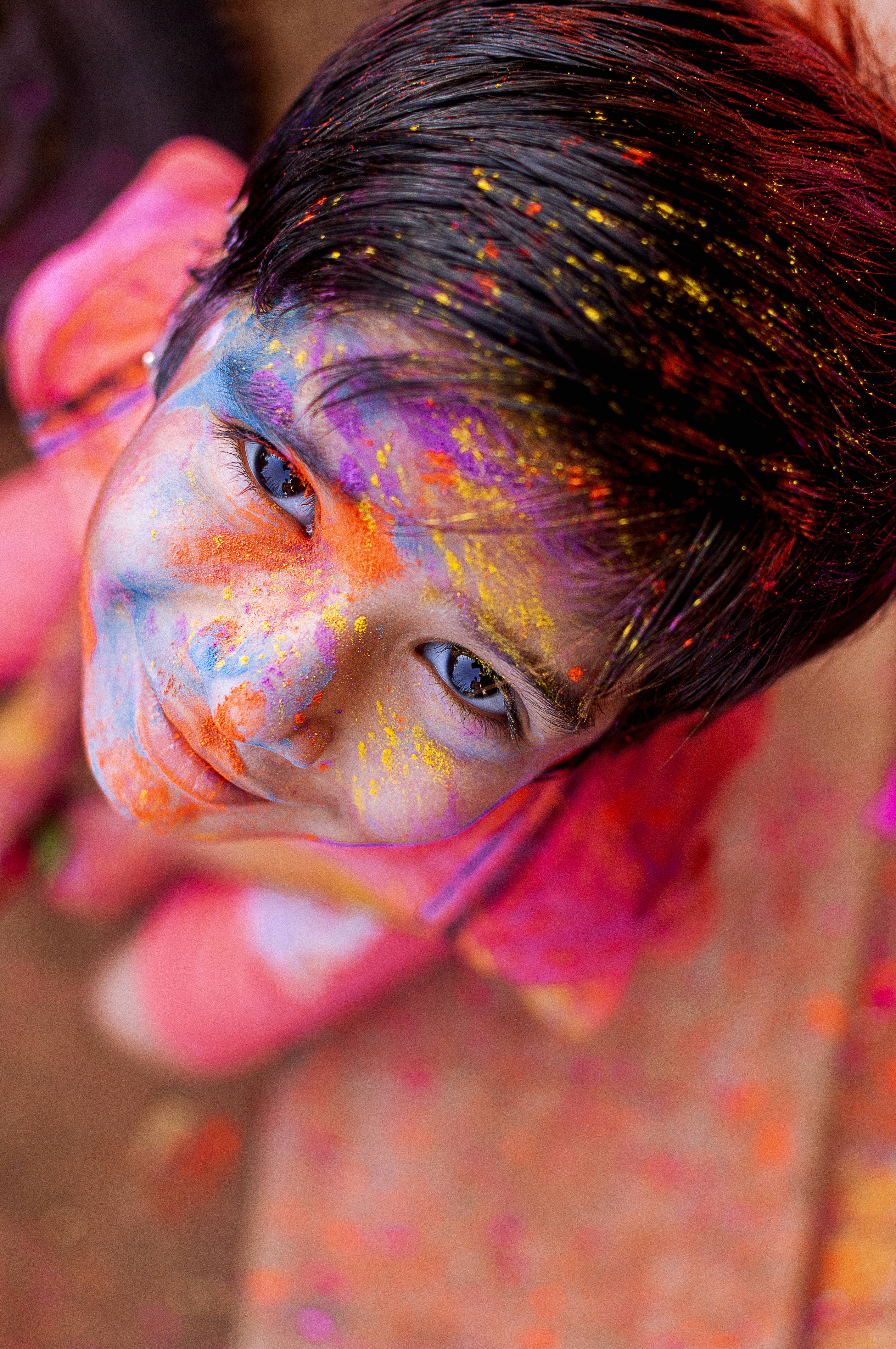 Holi 桌布 壁紙 — 一個快樂的孩子臉上和頭髮上沾滿鮮豔的彩色粉末，在節日慶祝活動中對著鏡頭微笑。