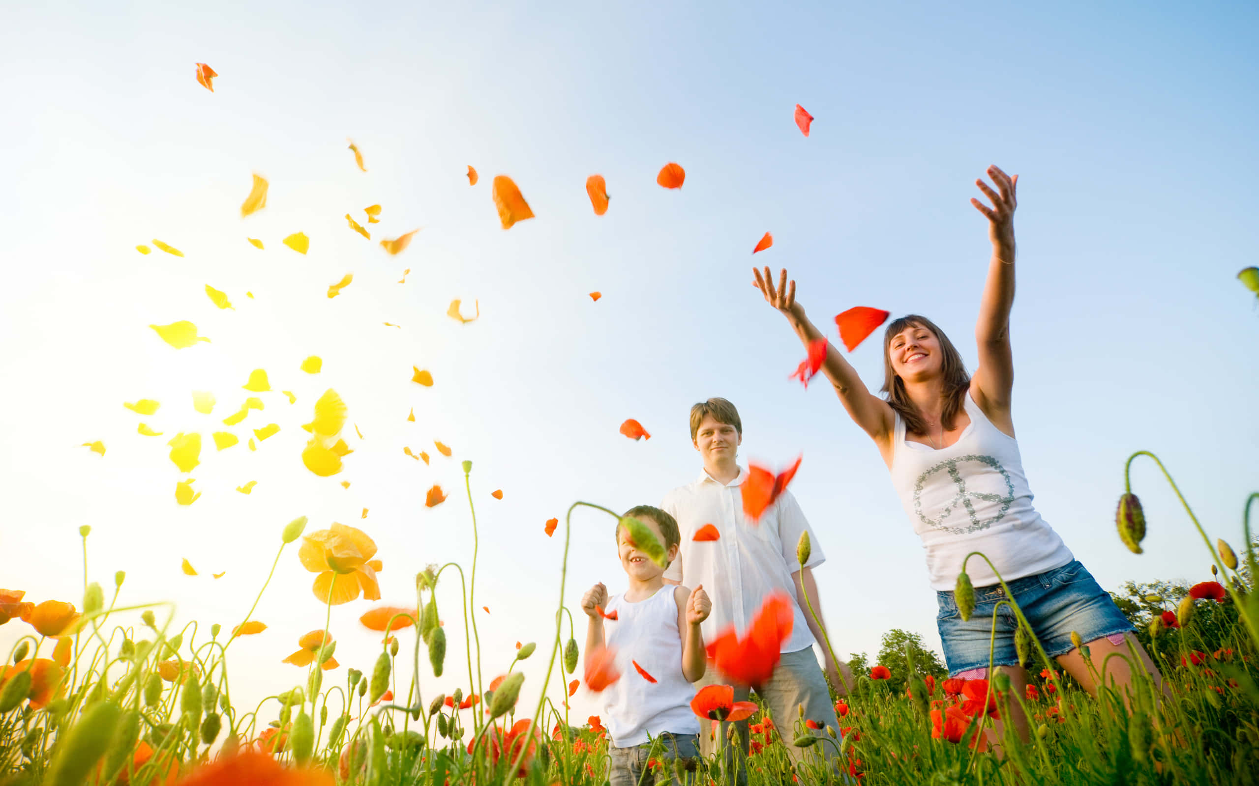 Spring Family 桌布 壁紙 — 一個快樂的家庭在陽光明媚的日子裡笑著將鮮豔的橙色罌粟花瓣拋向明亮的藍天。