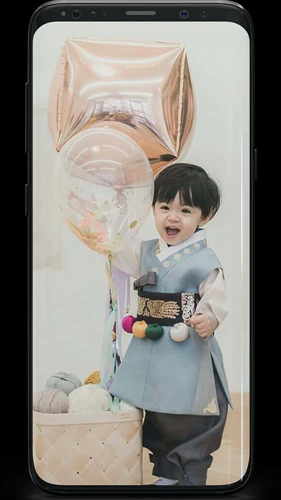 Balloon 桌布 壁紙 — 一個快樂的幼兒穿著傳統韓服，拿著玫瑰金和透明的五彩紙屑氣球，旁邊放著一籃紗線。