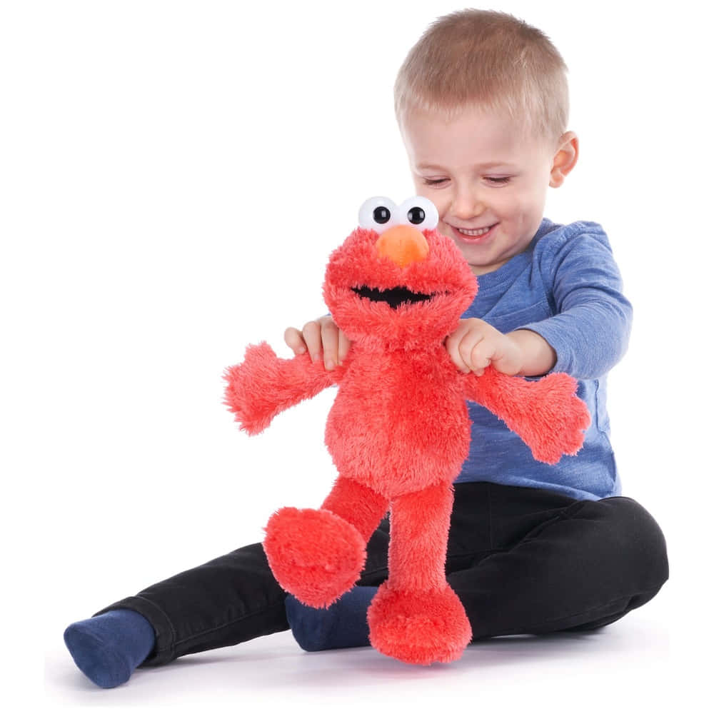 Elmo 桌布 壁紙 — 一個快樂的幼兒穿著藍色襯衫，在純白背景前抱著一個毛茸茸的紅色 Elmo 絨毛玩具。