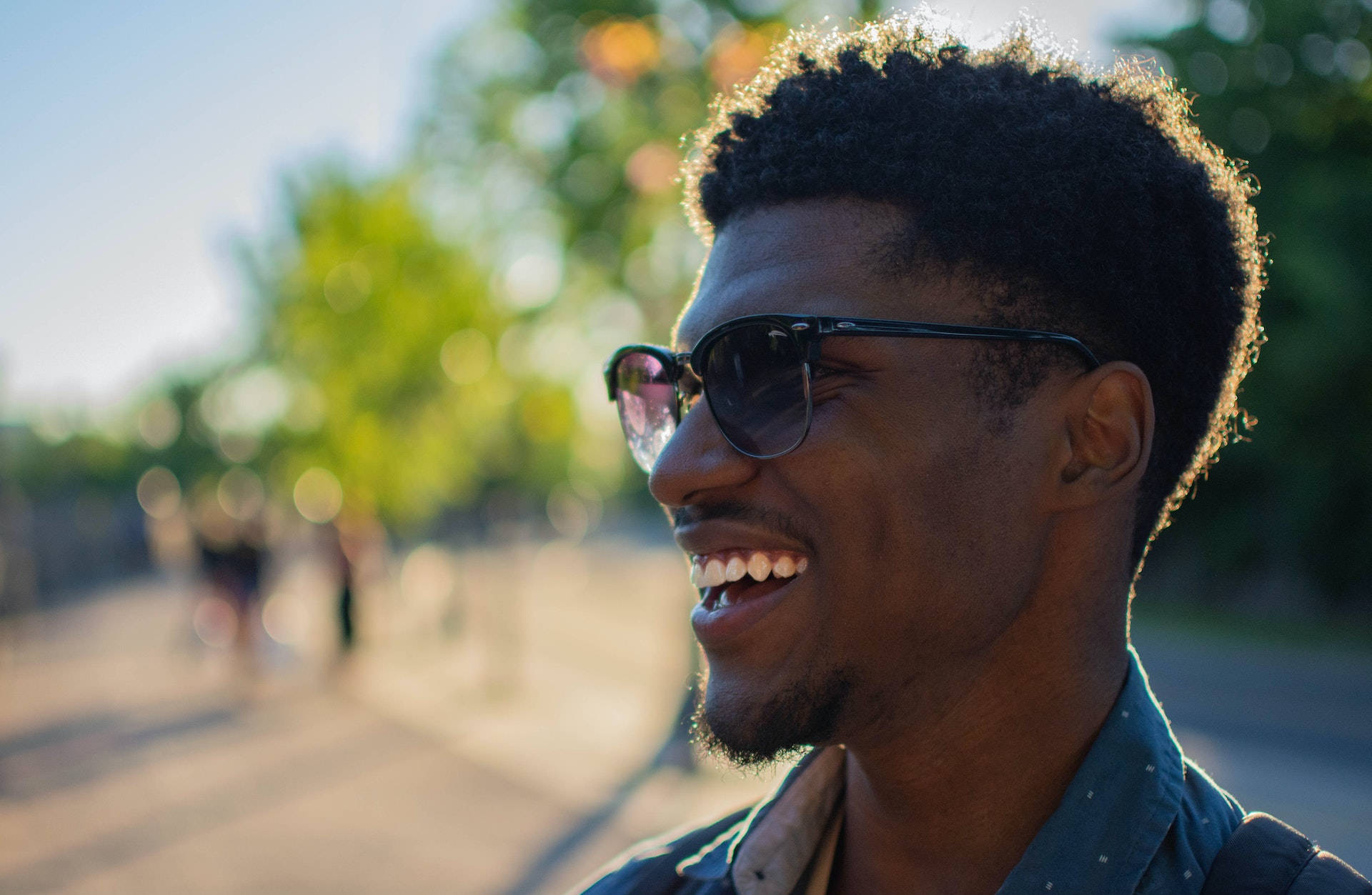 Sunglasses 桌布 壁紙 — 一個快樂的捲髮男子戴著太陽眼鏡，在金色陽光下開懷大笑。