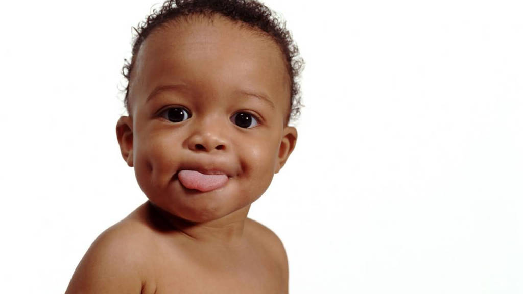 Funny Baby 桌布 壁紙 — 一個快樂的深色捲髮嬰兒在純白色背景上頑皮地伸出舌頭。