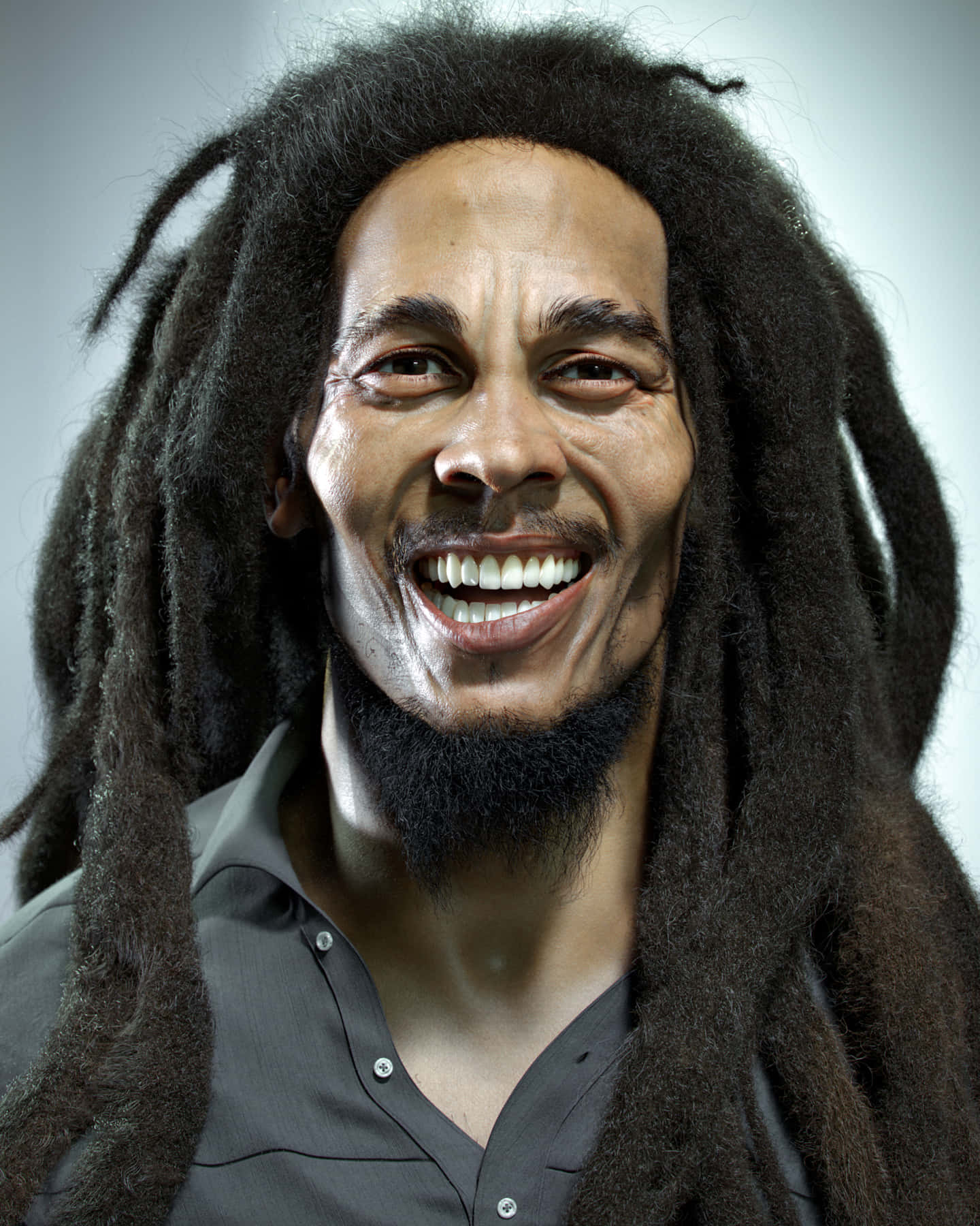 Bob Marley 桌布 壁紙 — 一個快樂的男人，留著長長的深色辮子，露出寬闊的笑容，背景是純灰色。