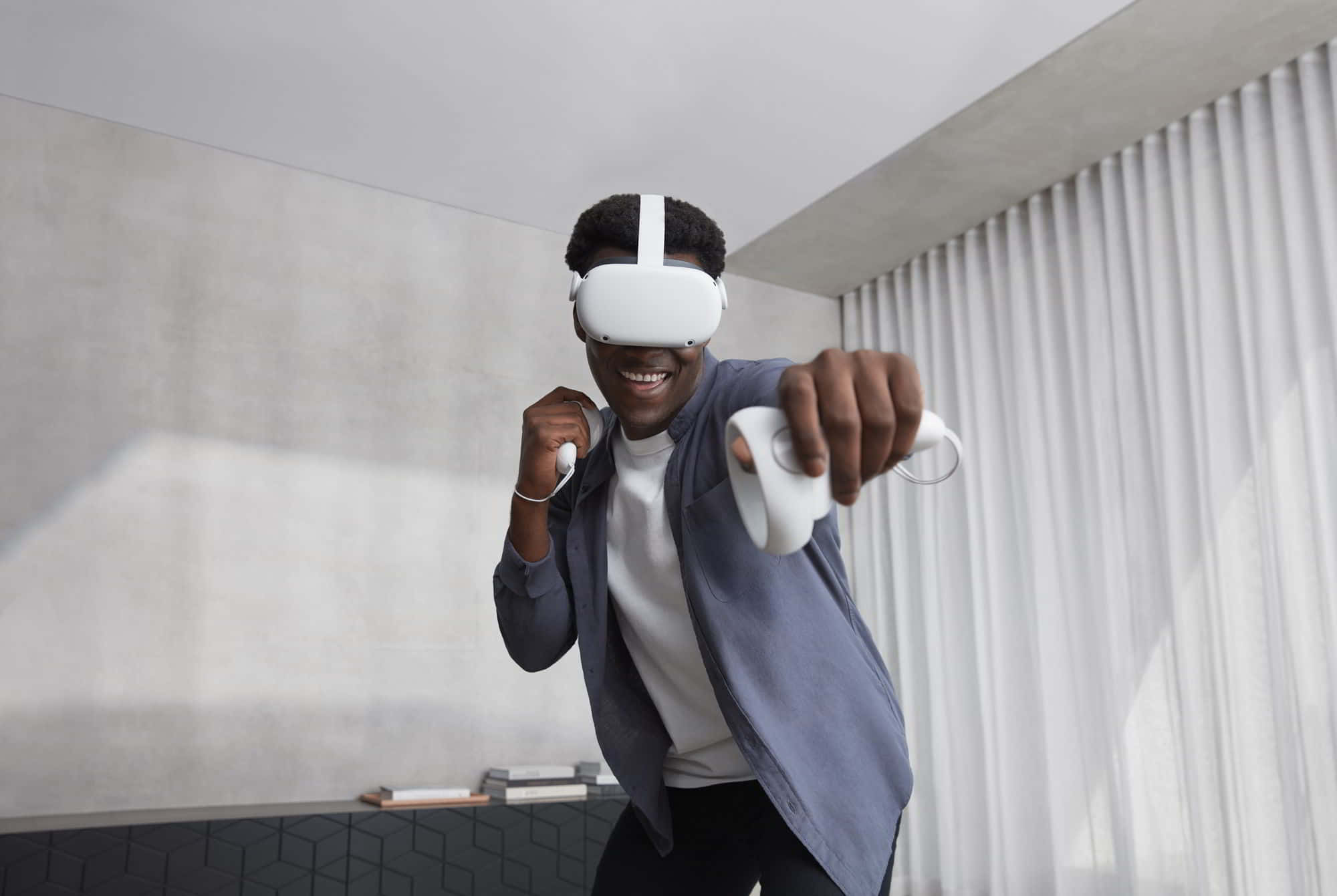 Oculus Quest 2 桌布 壁紙 — 一個快樂的男人在現代房間裡戴著白色VR頭戴式裝置，手持控制器，充滿活力地微笑。