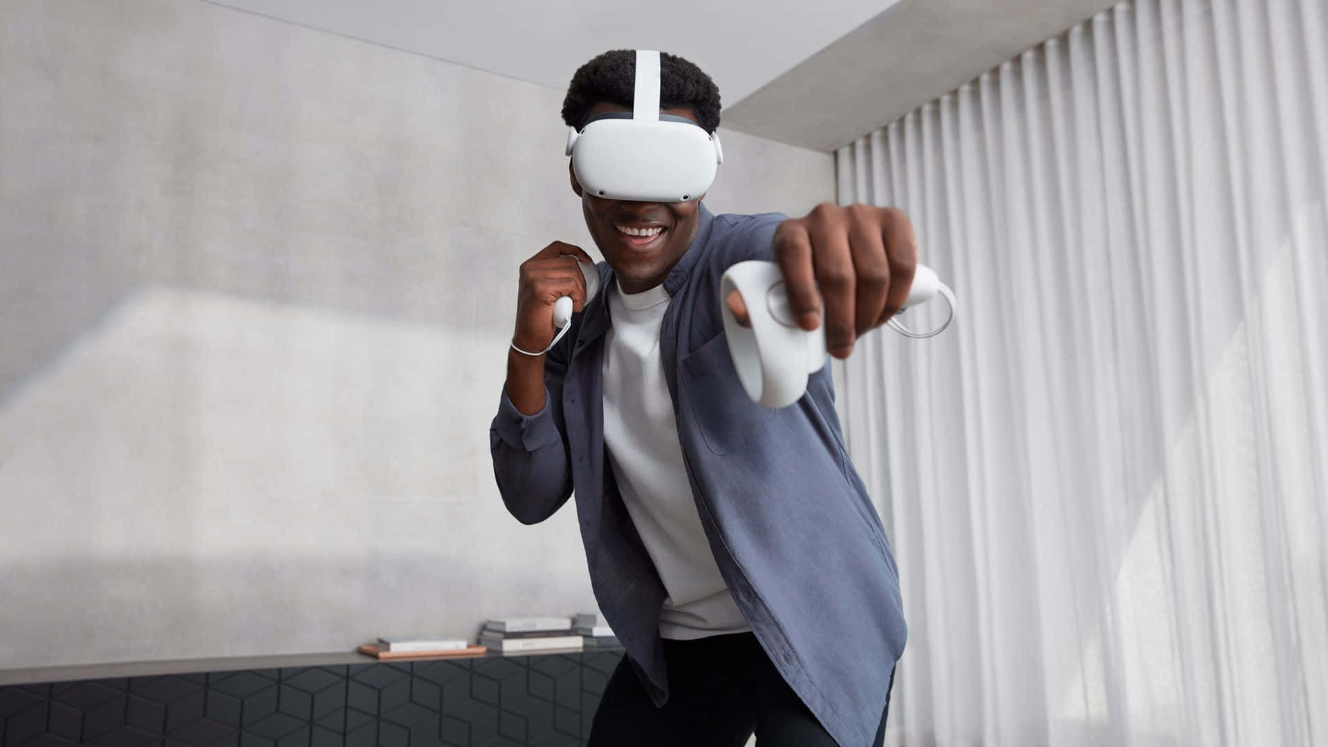 Oculus Quest 2 桌布 壁紙 — 一個快樂的男人在現代房間裡戴著白色VR頭戴式顯示器，手持控制器，充滿活力地微笑。