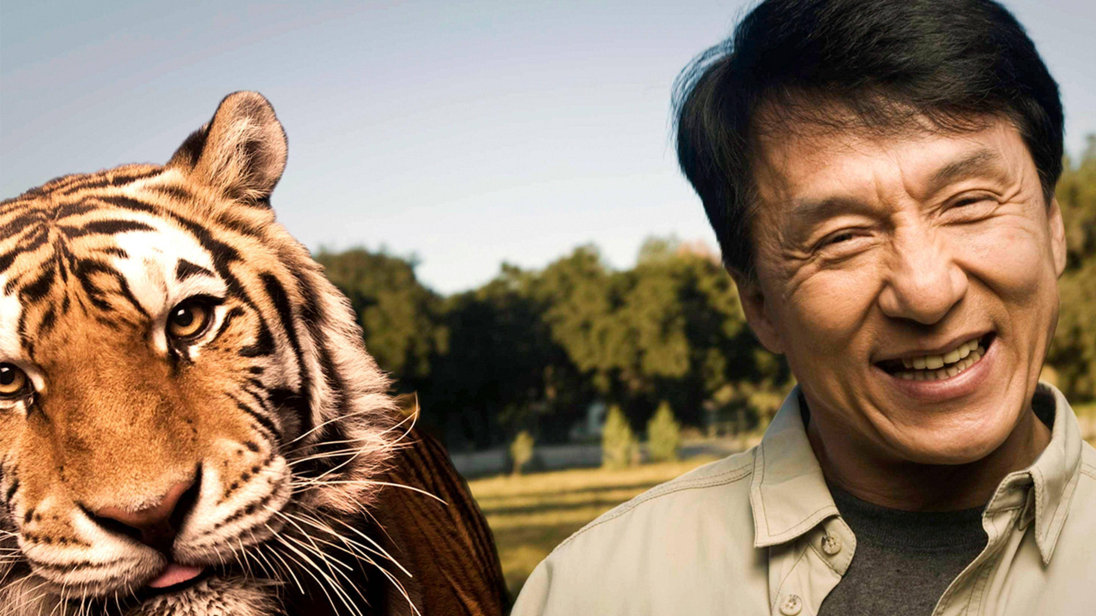 動物 桌布 壁紙 — 一個快樂的男人在陽光普照的戶外環境中，微笑著站在老虎的特寫旁邊。