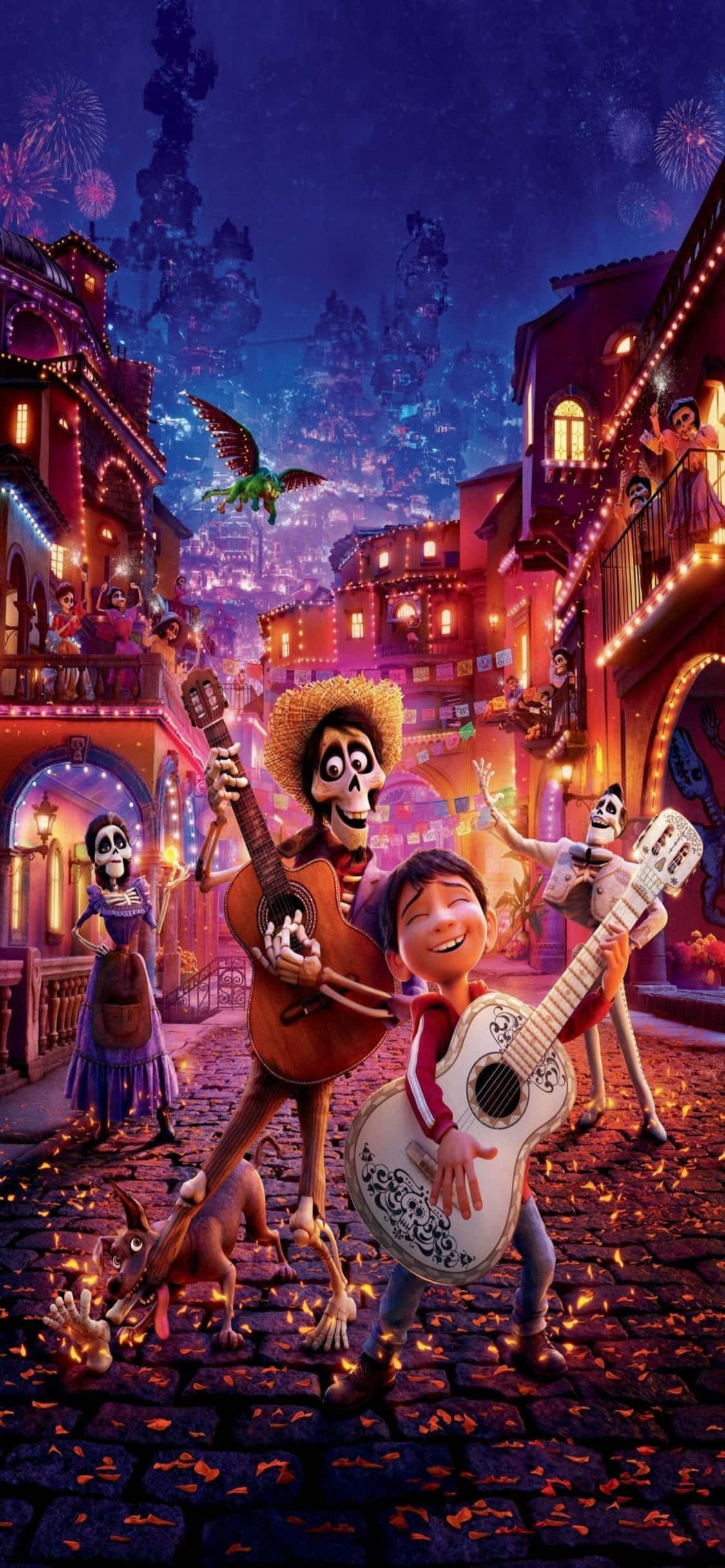 可可 桌布 壁紙 — 一個快樂的男孩和骷髏瑪利亞奇音樂家在夜晚燈籠照亮、充滿活力的墨西哥街道上彈吉他，伴隨著煙火和發光的建築物。