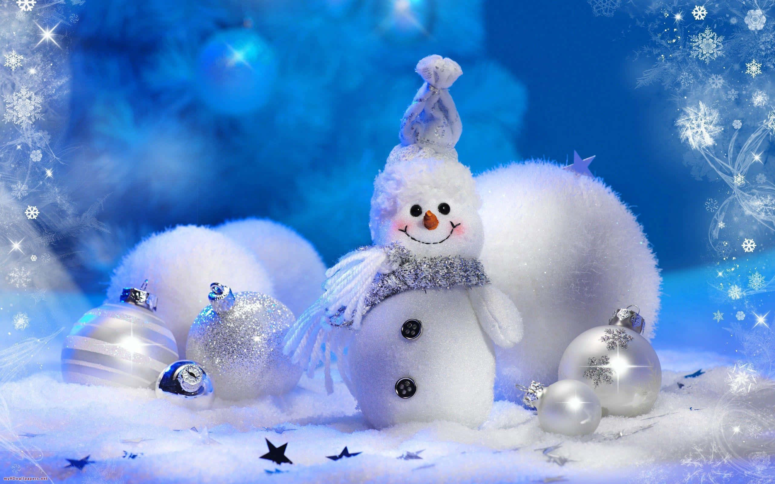 可愛聖誕節 桌布 壁紙 — 一個快樂的雪人，戴著閃閃發光的圍巾和帽子，站在雪白的藍色冬日場景中，周圍環繞著銀色裝飾品和閃爍的雪花。