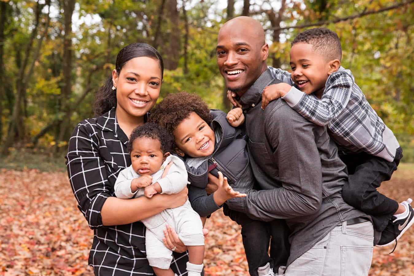 Black Family 桌布 壁紙 — 一個快樂的非裔美國五人家庭在秋天的森林中溫暖微笑，腳下滿是落葉。