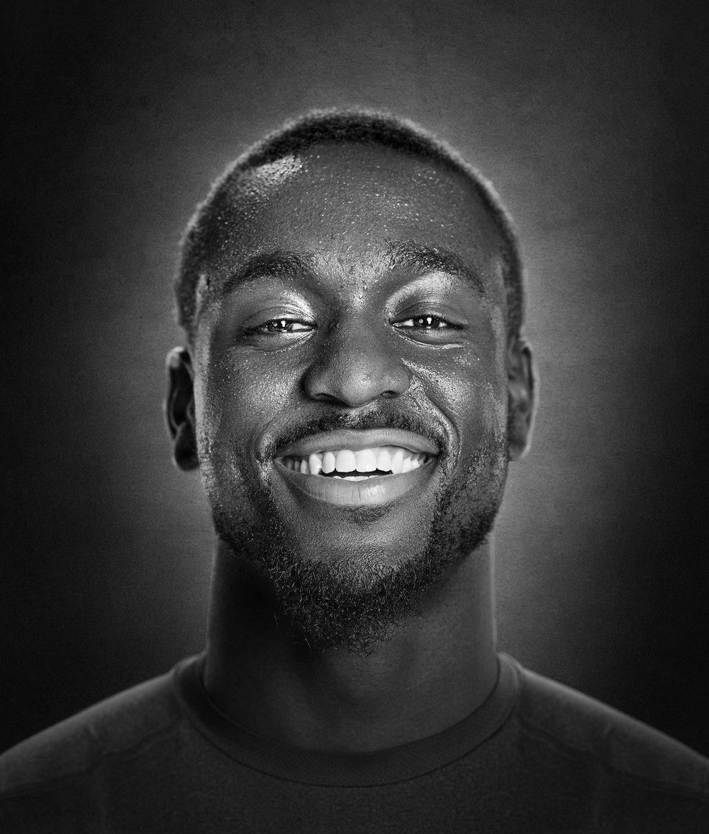 Kemba Walker 桌布 壁紙 — 一個快樂的黑白肖像，一個微笑的男人，在柔和的漸變背景前展現燦爛的表情。