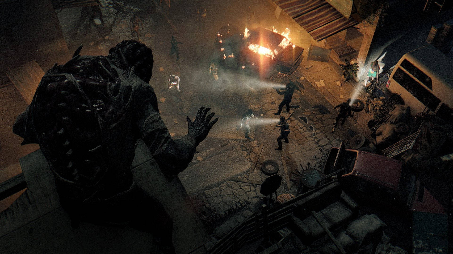 Dying Light 桌布 壁紙 — 一個怪物般的身影聳立在混亂的街頭戰鬥之上，有武裝人物和燃燒的車輛，在昏暗的橙色光芒下。