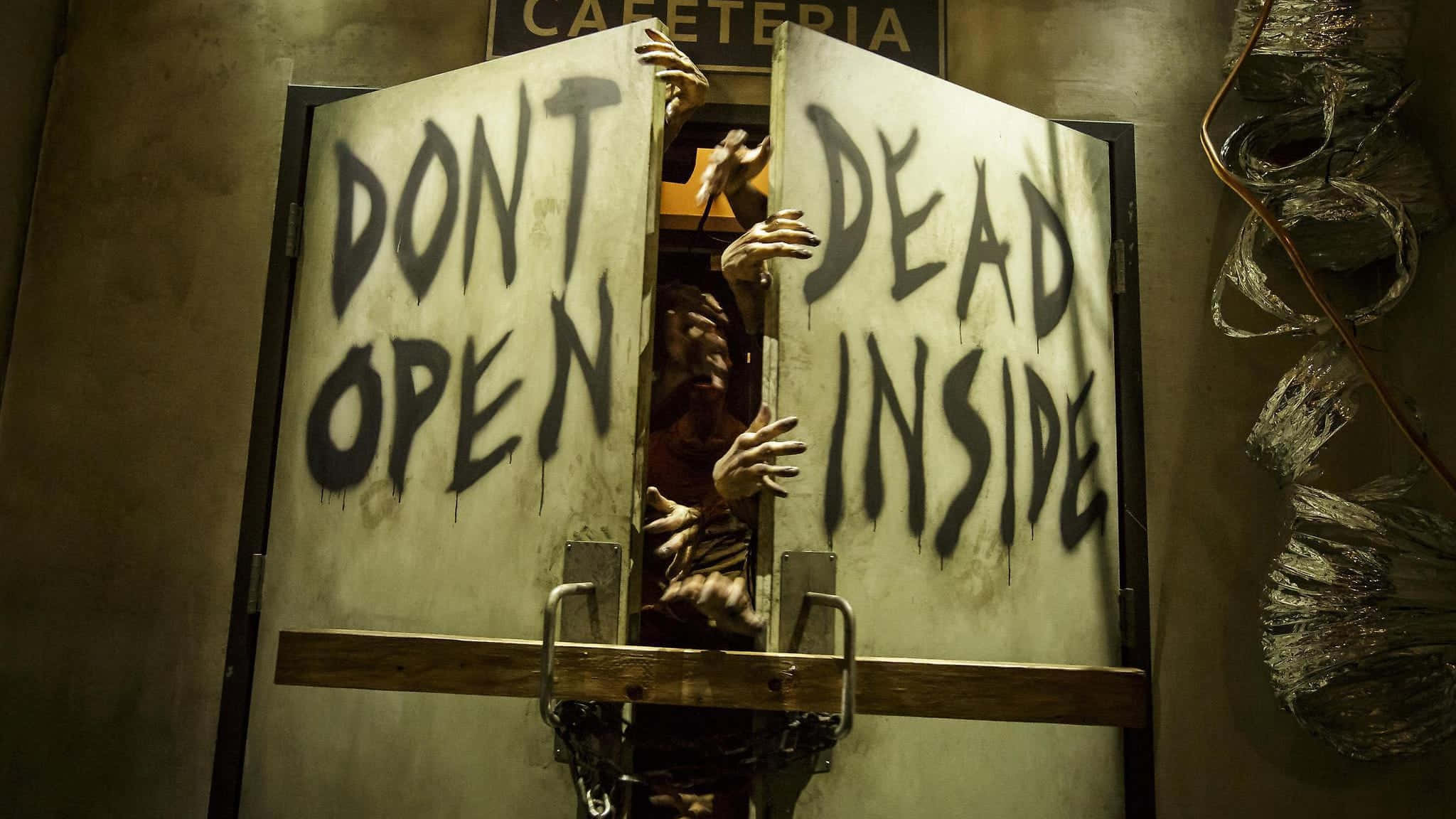 Dead Inside 桌布 壁紙 — 一個怪誕的殭屍用腐爛的手抓住一扇寫著「DONT OPEN DEAD INSIDE」的設有路障的門，在燈光昏暗的自助餐廳裡。