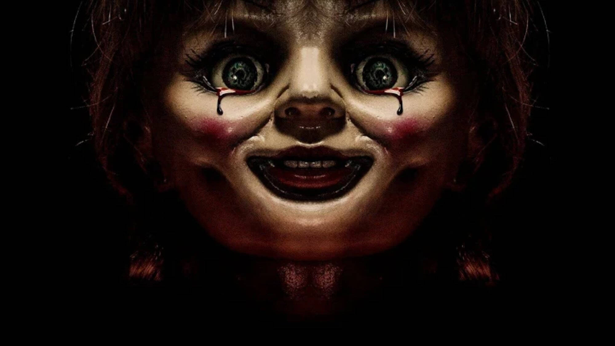 Annabelle 桌布 壁紙 — 一個恐怖娃娃的特寫，擁有綠色大眼睛，血淚從臉頰滴下，背景為黑色。